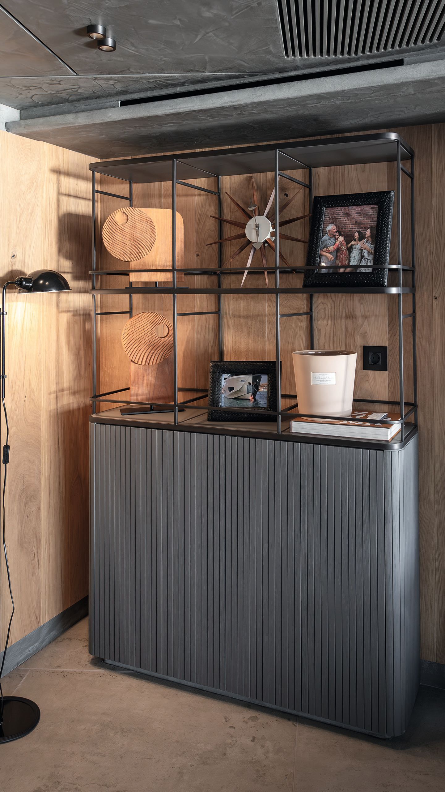 Dark grey shelving unit with cupboard underneath. Abstract sculptures and pictures are on the shelves