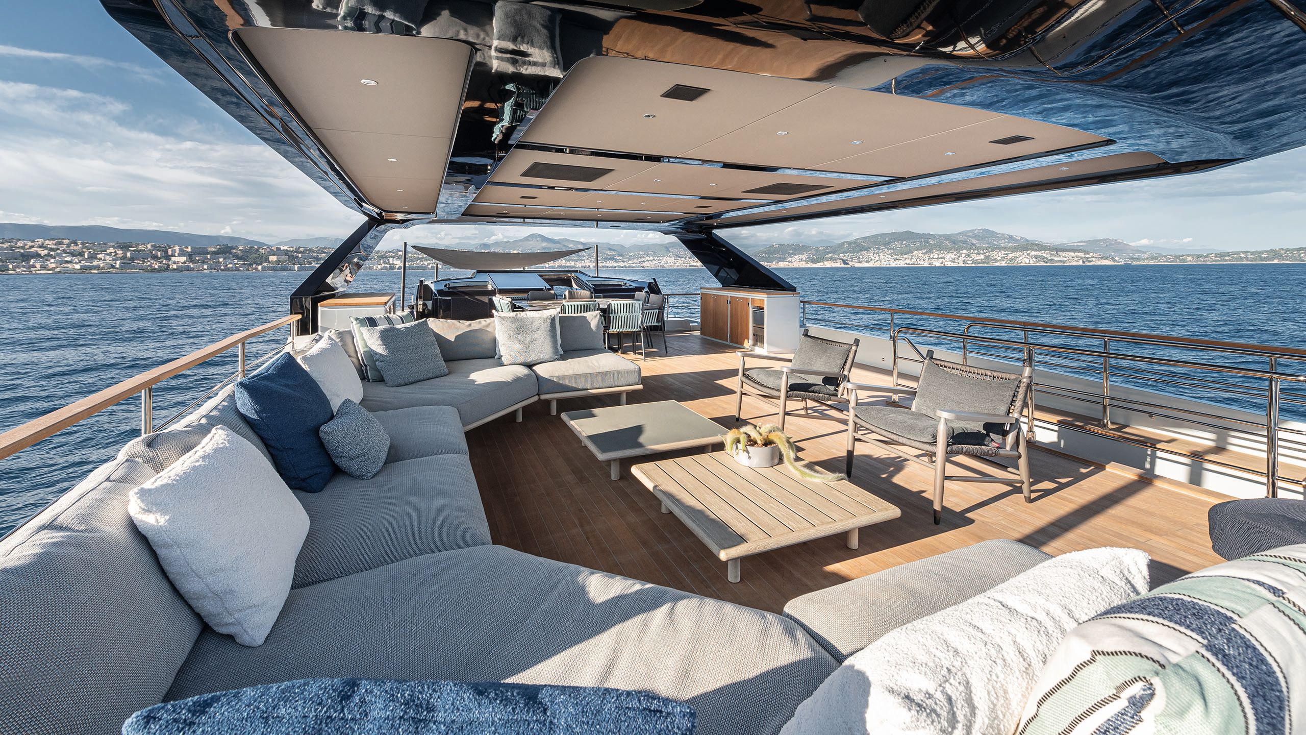 Covered deck area with u-shaped lounge seating and loose armchairs