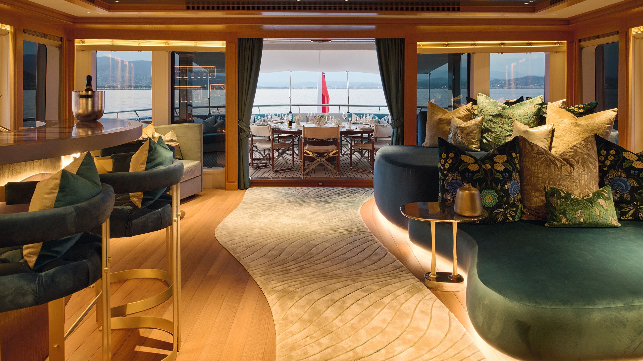 The salon now has a bar on the left with velvet stools in teal. On the right are large seat pads in teal with huge throw cushions