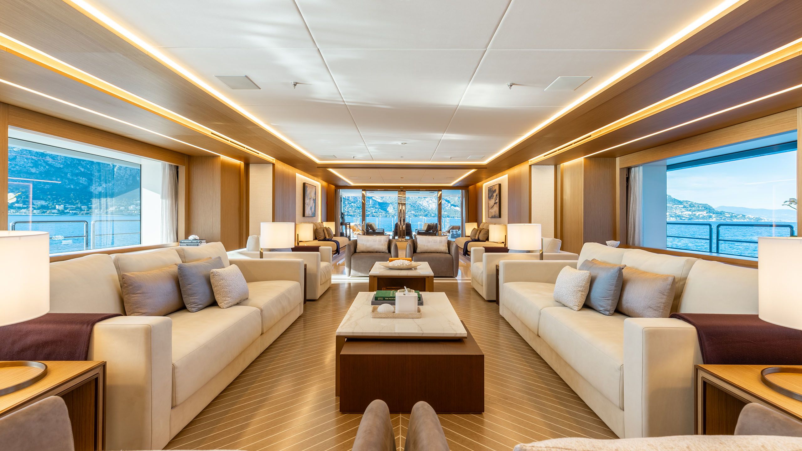 Interior shot of lounge area on Alfa. Two sofas face each other from either side of the room and a long table is inbetween them