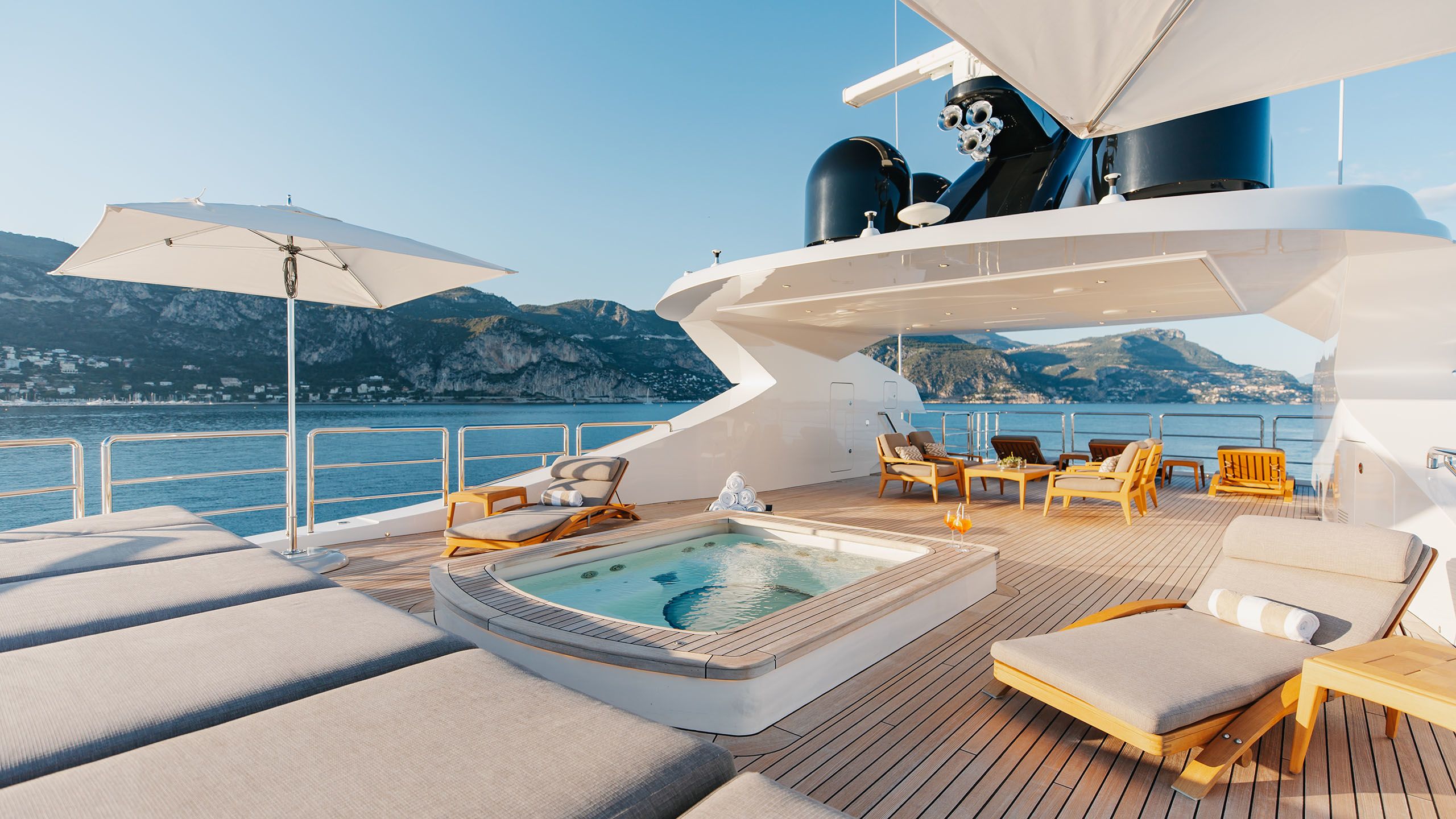 Alfa deck area showing large parasols shading sunloungers with grey cushions and a small rectangular pool