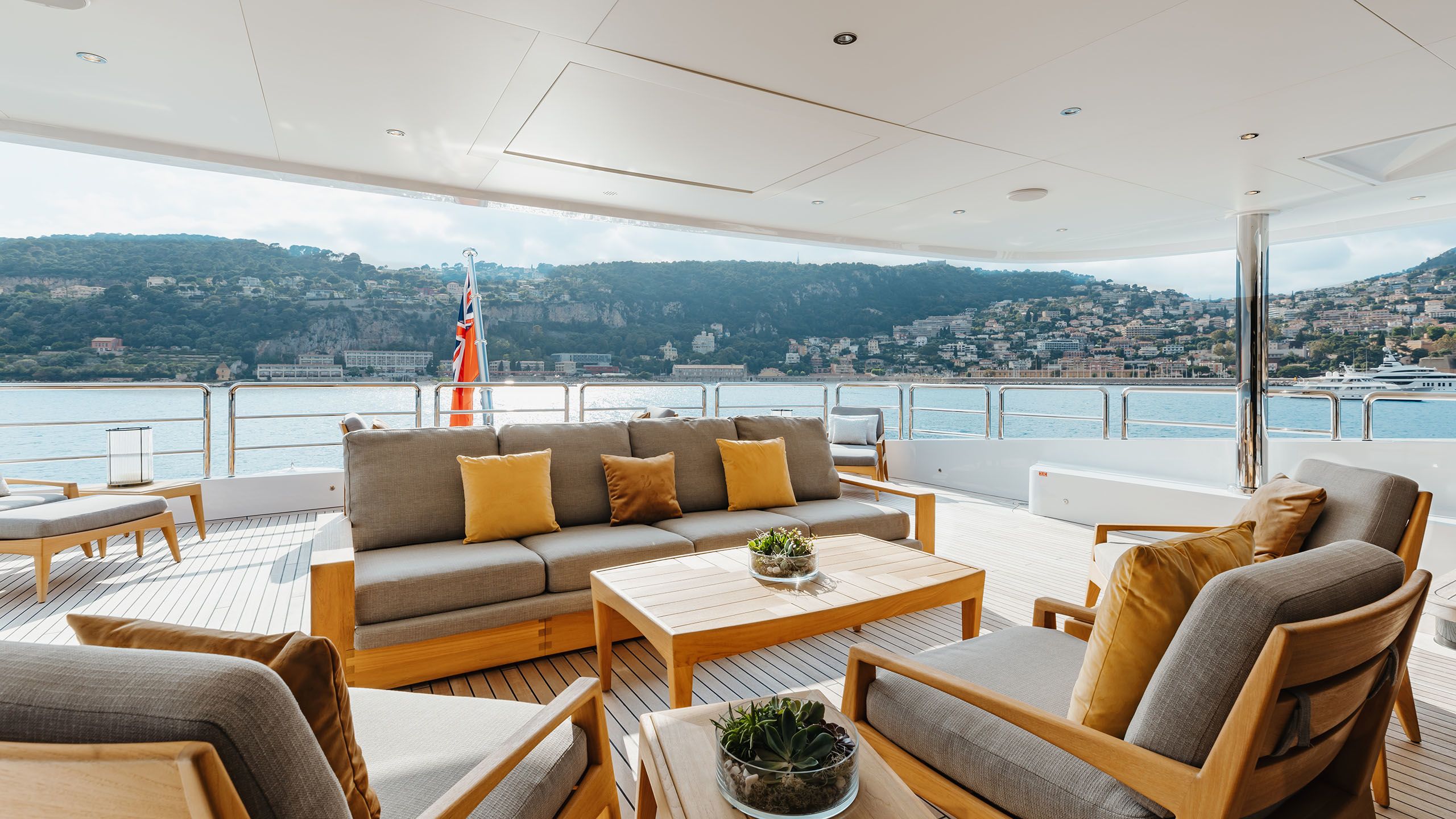 Alfa deck area showing a wooden sofa and chairs with grey cushion pads and yellow throw cushions