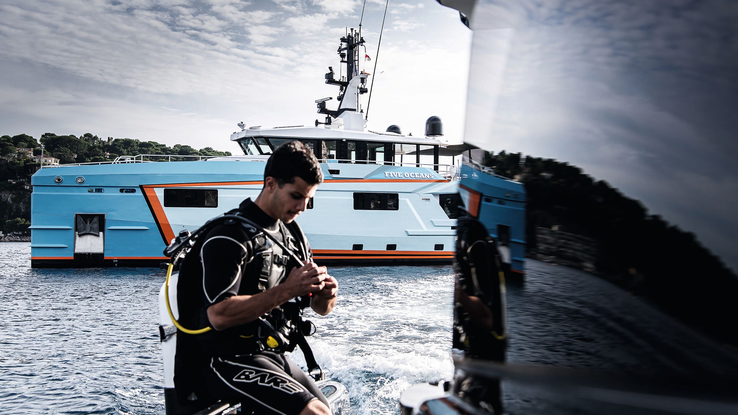 A man in diving gear walks in front of Five Oceans