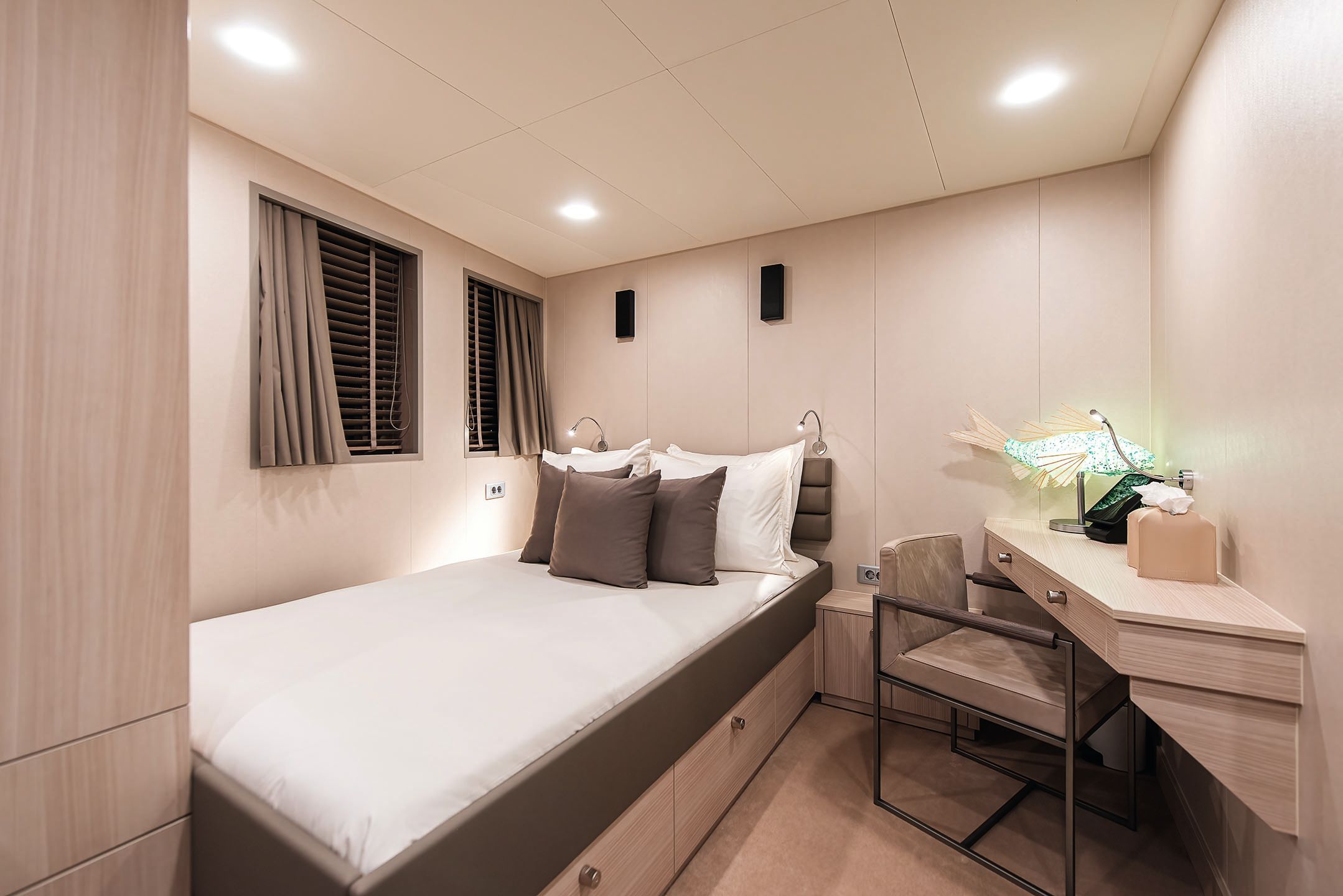 Small guest room with single bed, desk and chair done out in neutrals