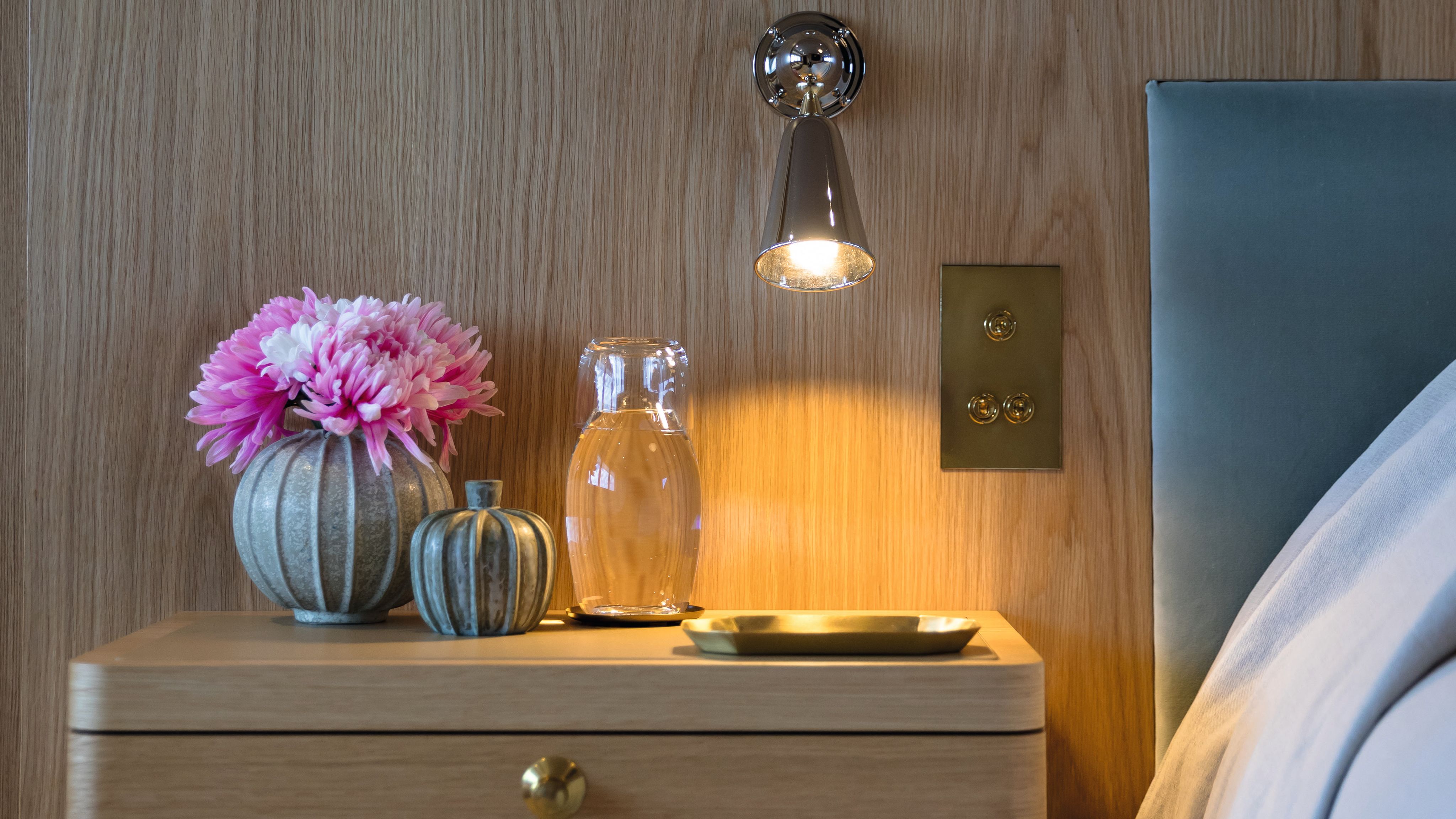 Close-up of the oak finish behind a bed headboard and bedside table