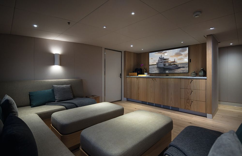 Snug-type room with u-shaped sofa and oak cabinet opposite with TV on the wall