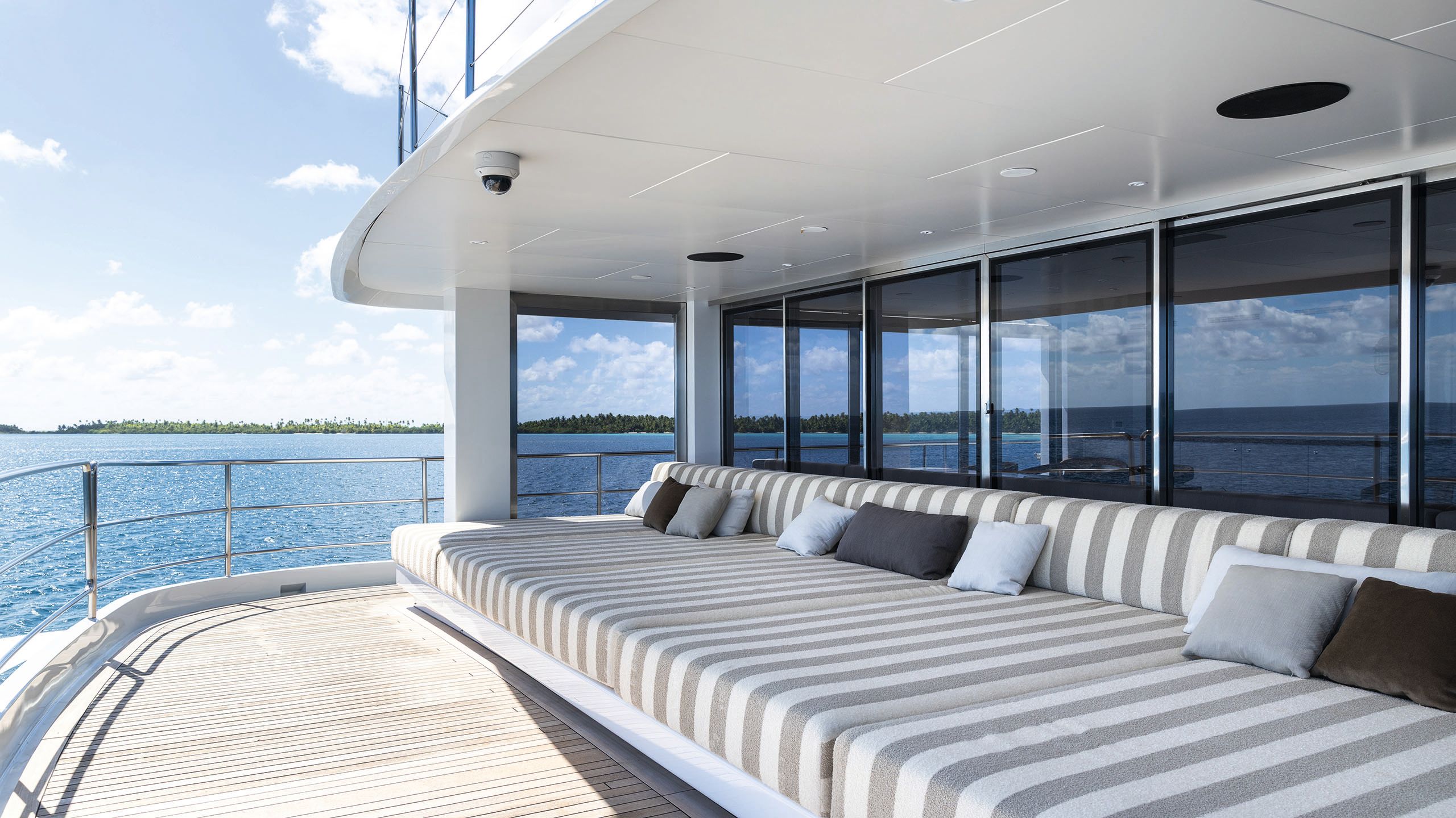 Sun loungers on the deck in grey and white stripe with throw cushions in blues and greys
