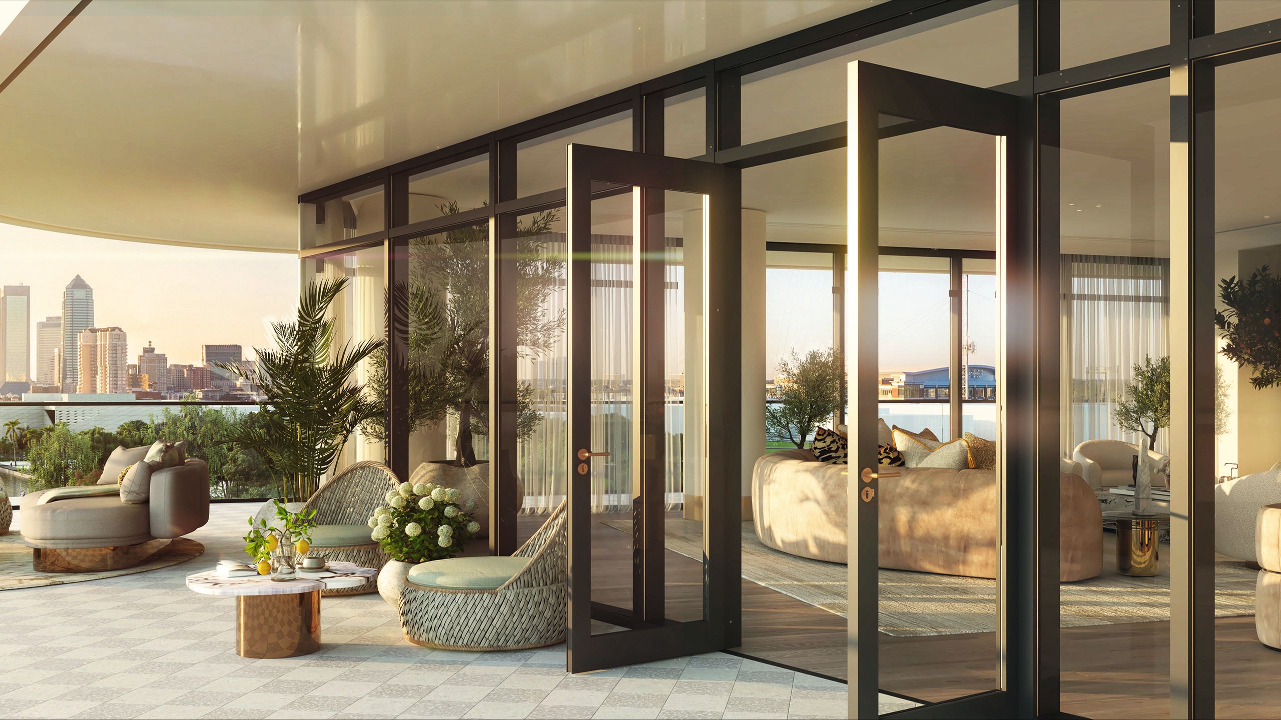 Outdoor area of the hotel - glass doors are open, leading on to a patio that has armchairs, tables and greenery/flowers