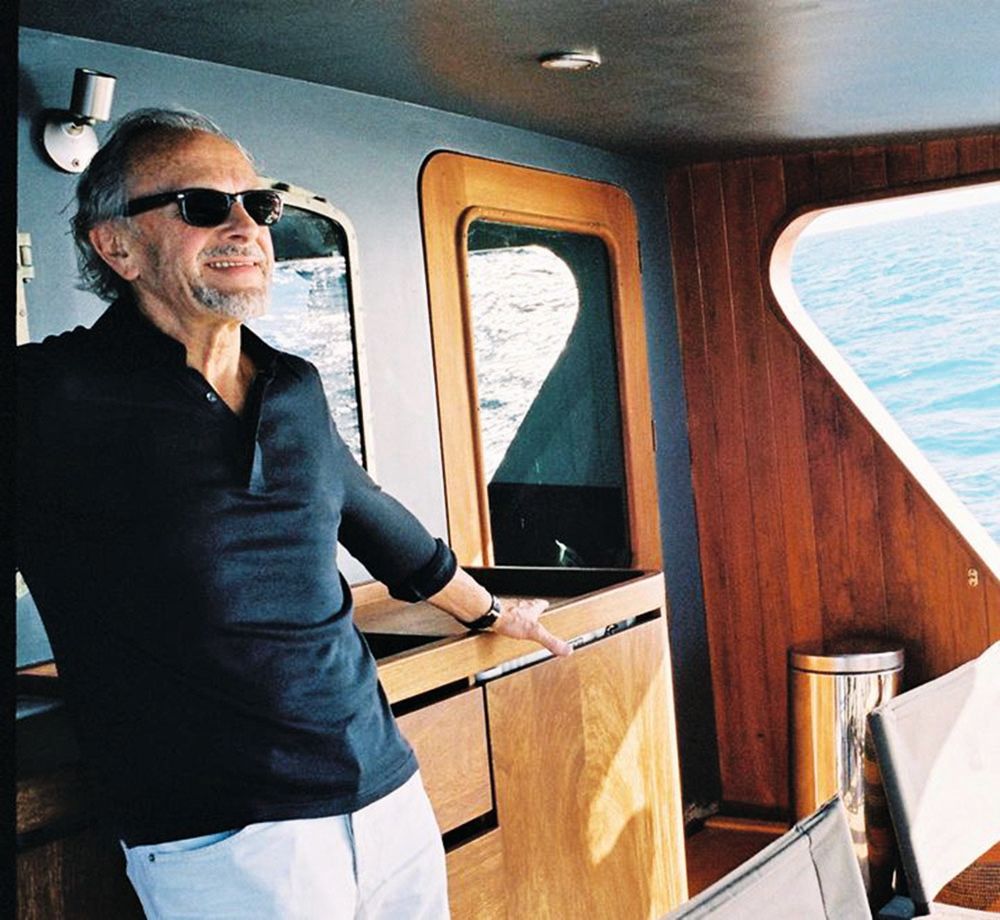 A man in a navy shirt, white trousers and sunglasses