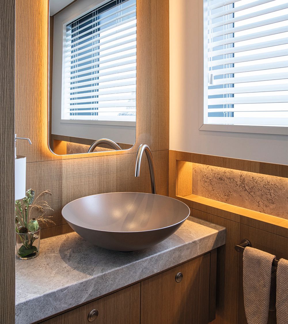 A portrait image of a large brown round sink with chrome tap over and mirror above