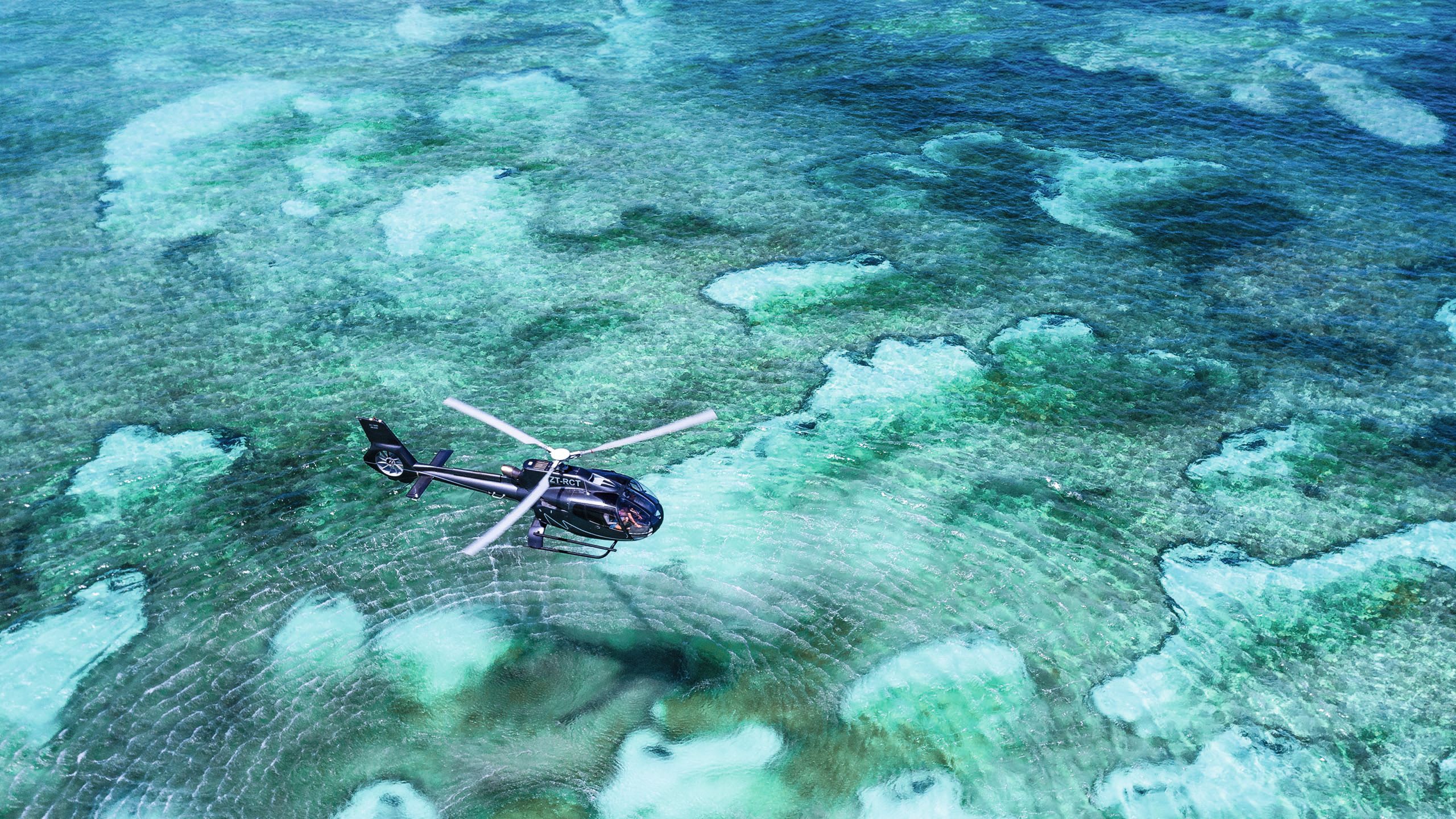 A helicopter flying over the turquoise ocean