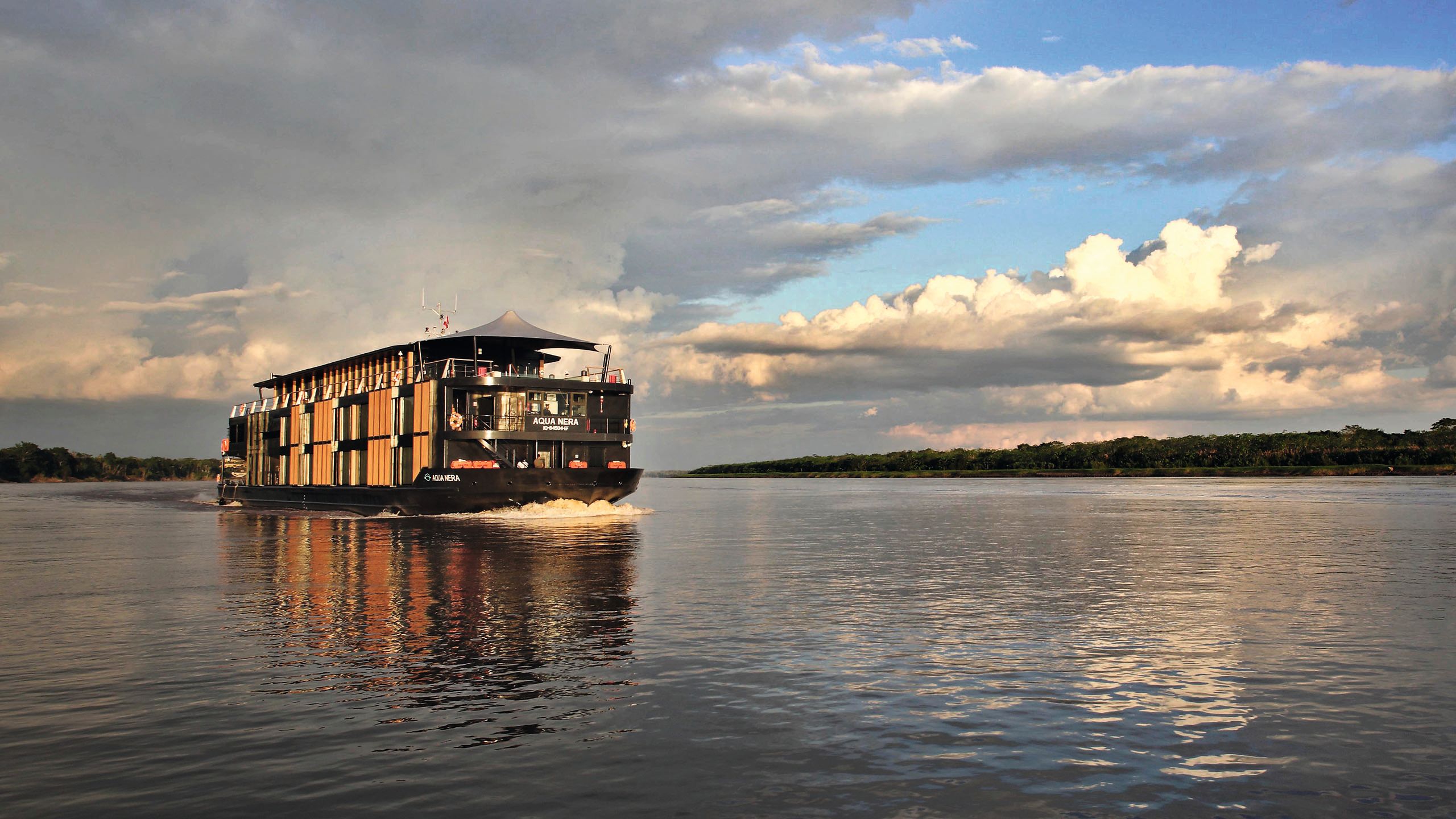 One of the yachts on the river - it has two storeys, floor to ceiling windows, and umbrellas on the top deck 
