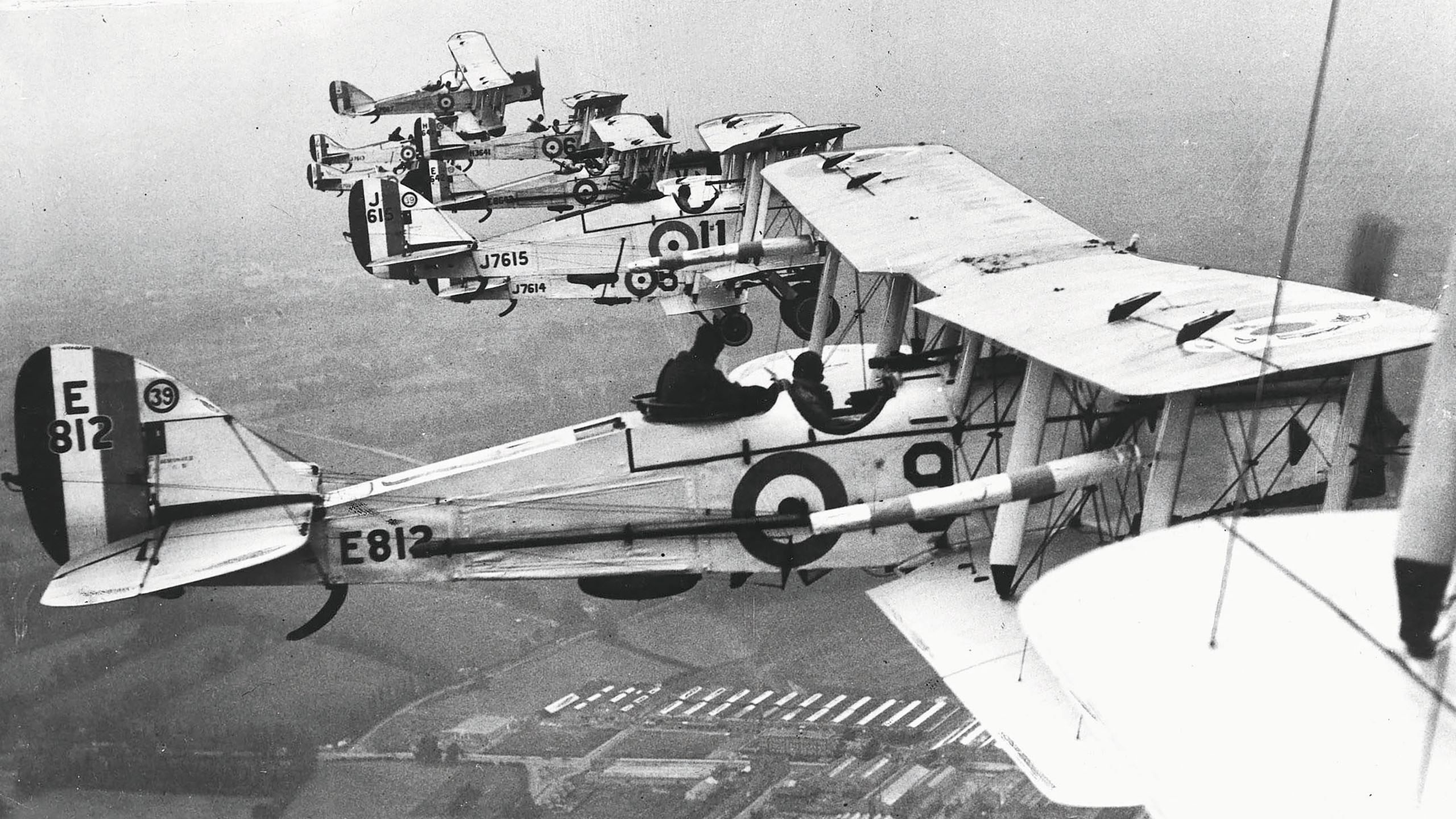Black and white photo of biplanes in the air
