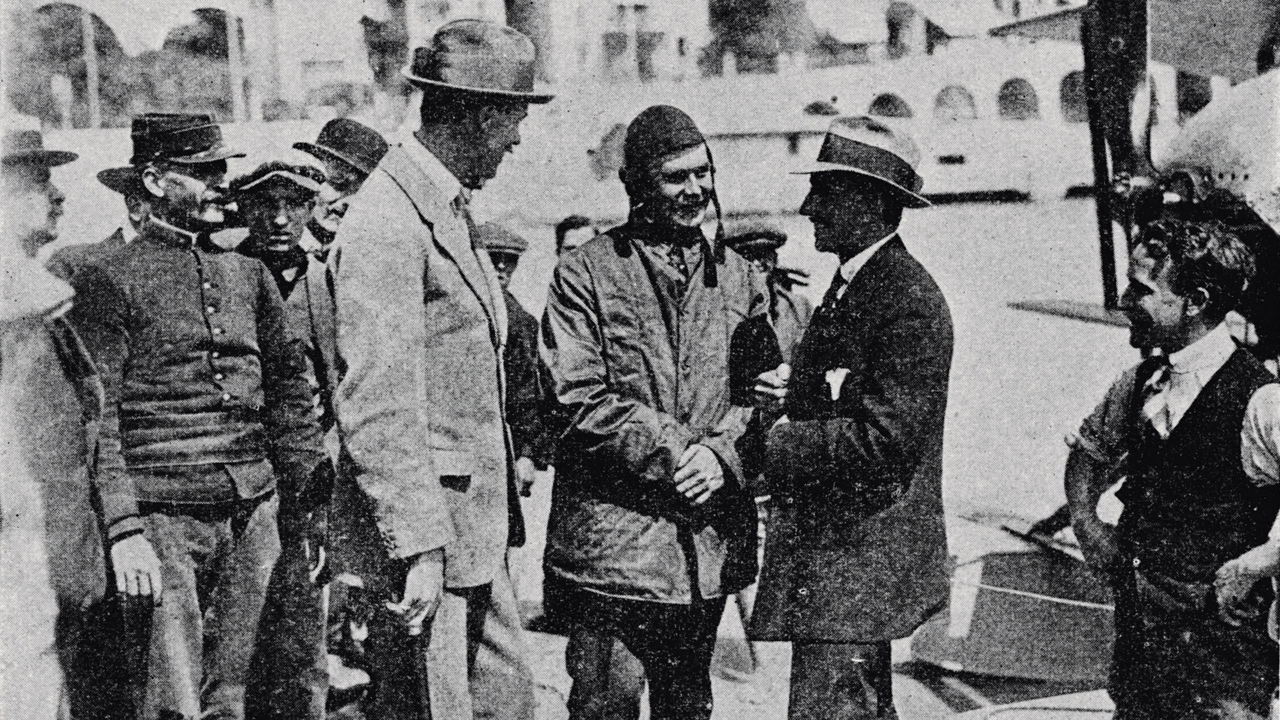 Black and white picture of Sopwith in airman clothing talking to two men in suits