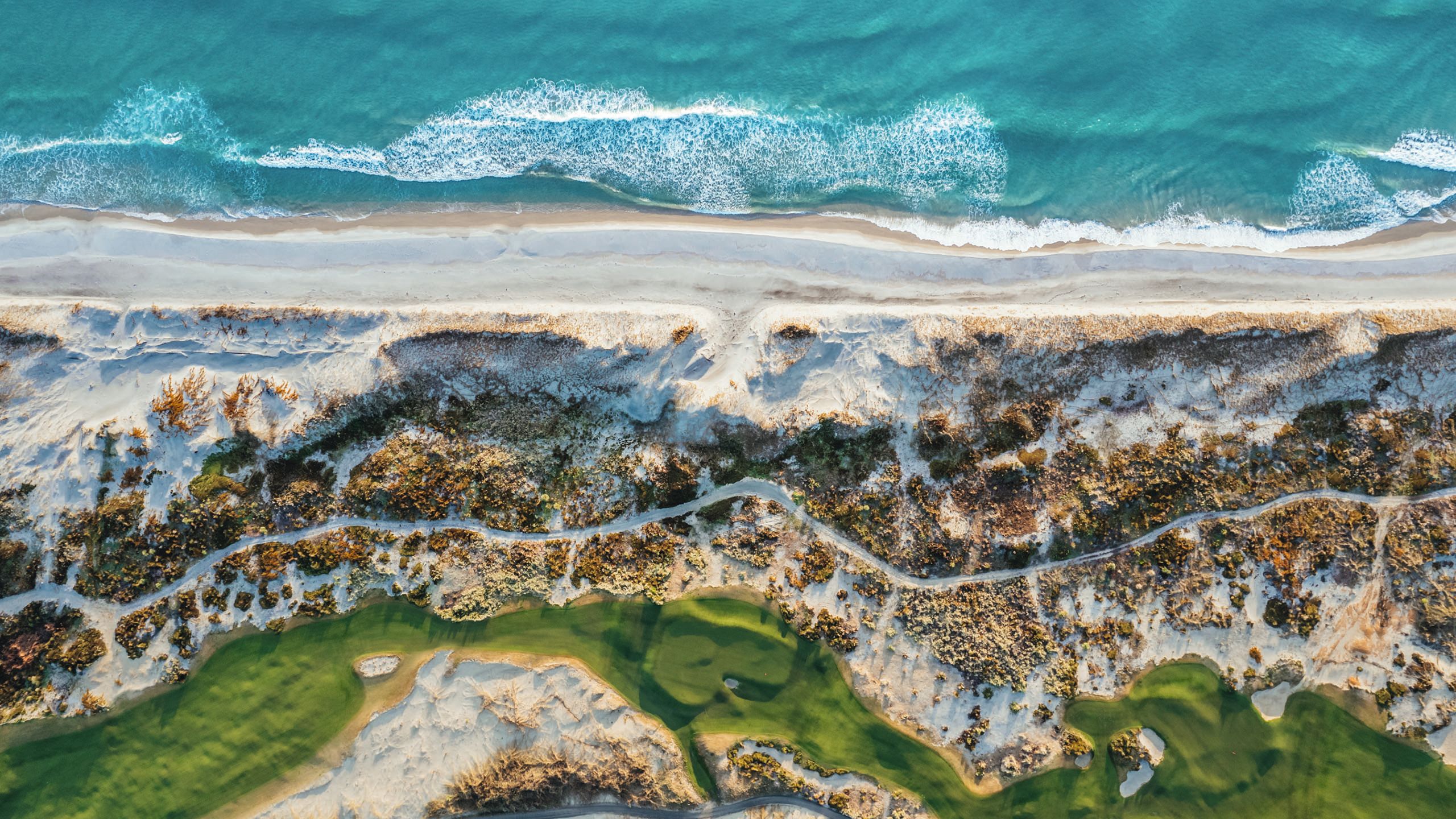 Overhead view of a golf course right by the beach