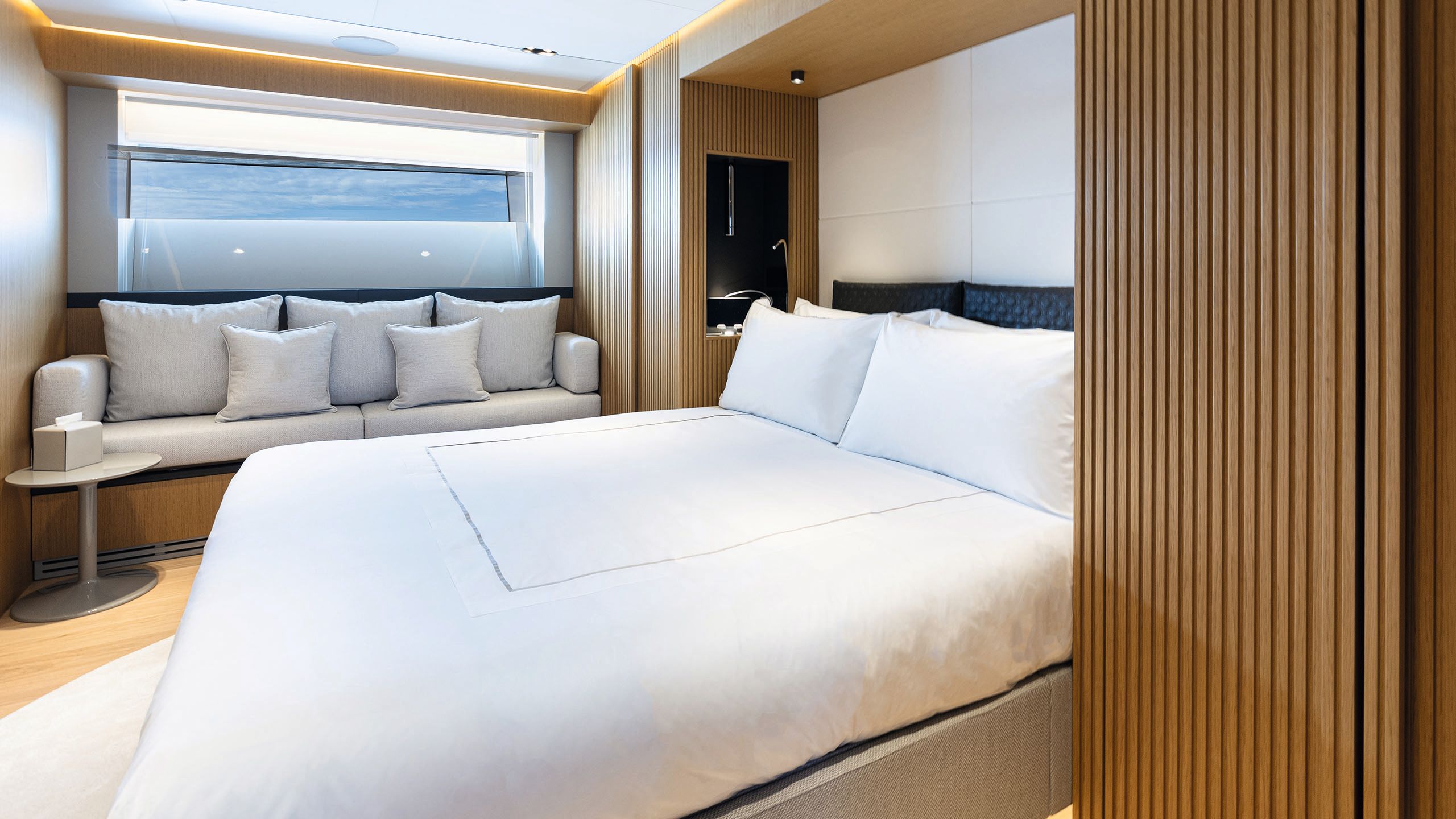 Guest cabin with bed made with white linens. A grey sofa bed is opposite