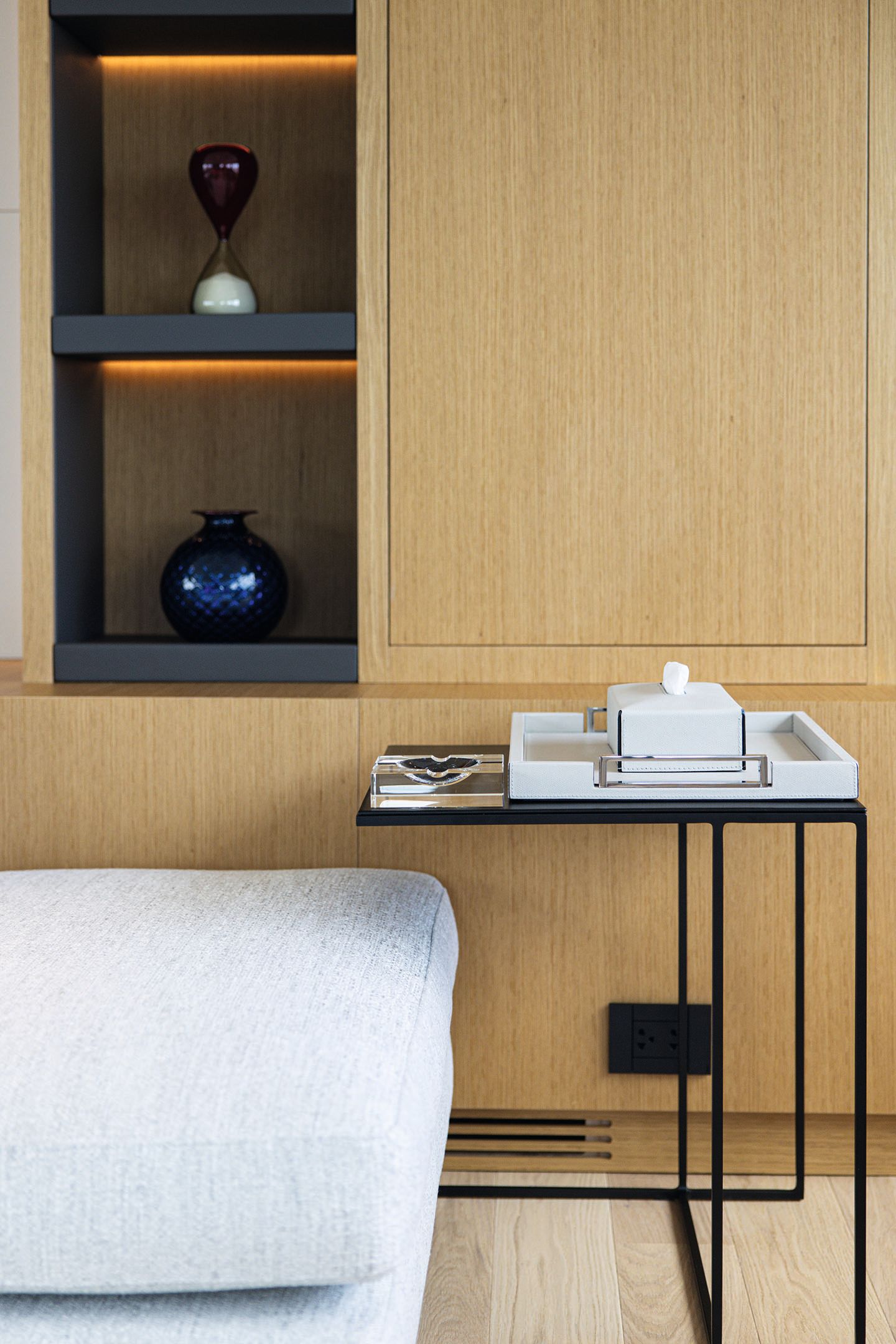 Close-up of oak cupboard, black table with blue vase on a shelf