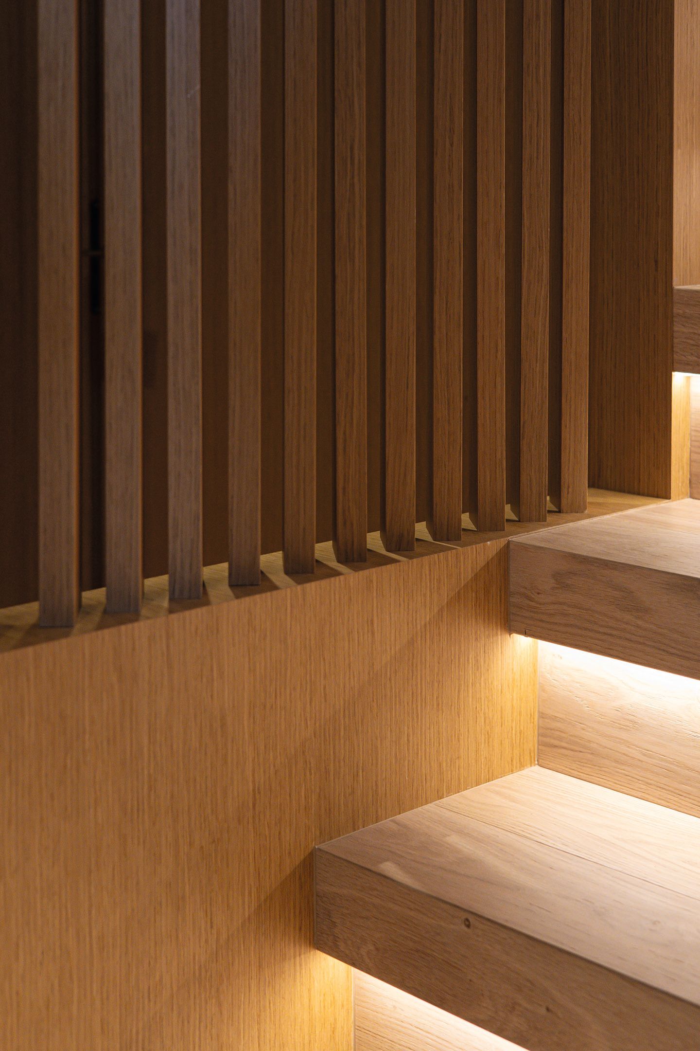 Close-up of oak panelling on a staircase that has treads lit from underneath
