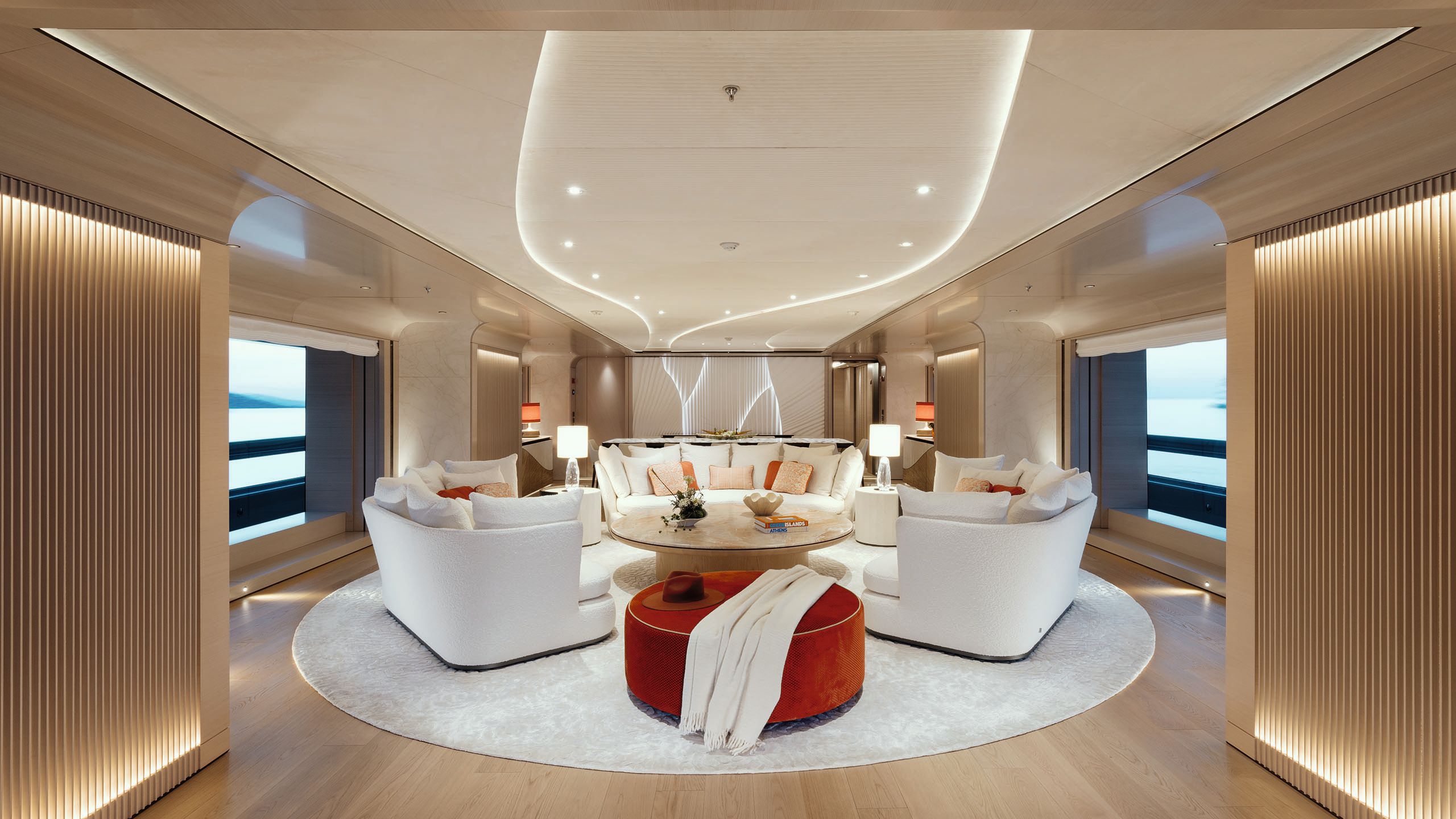 Agate table at the back of the dining room with three white sofas in front and a red footstool in foreground