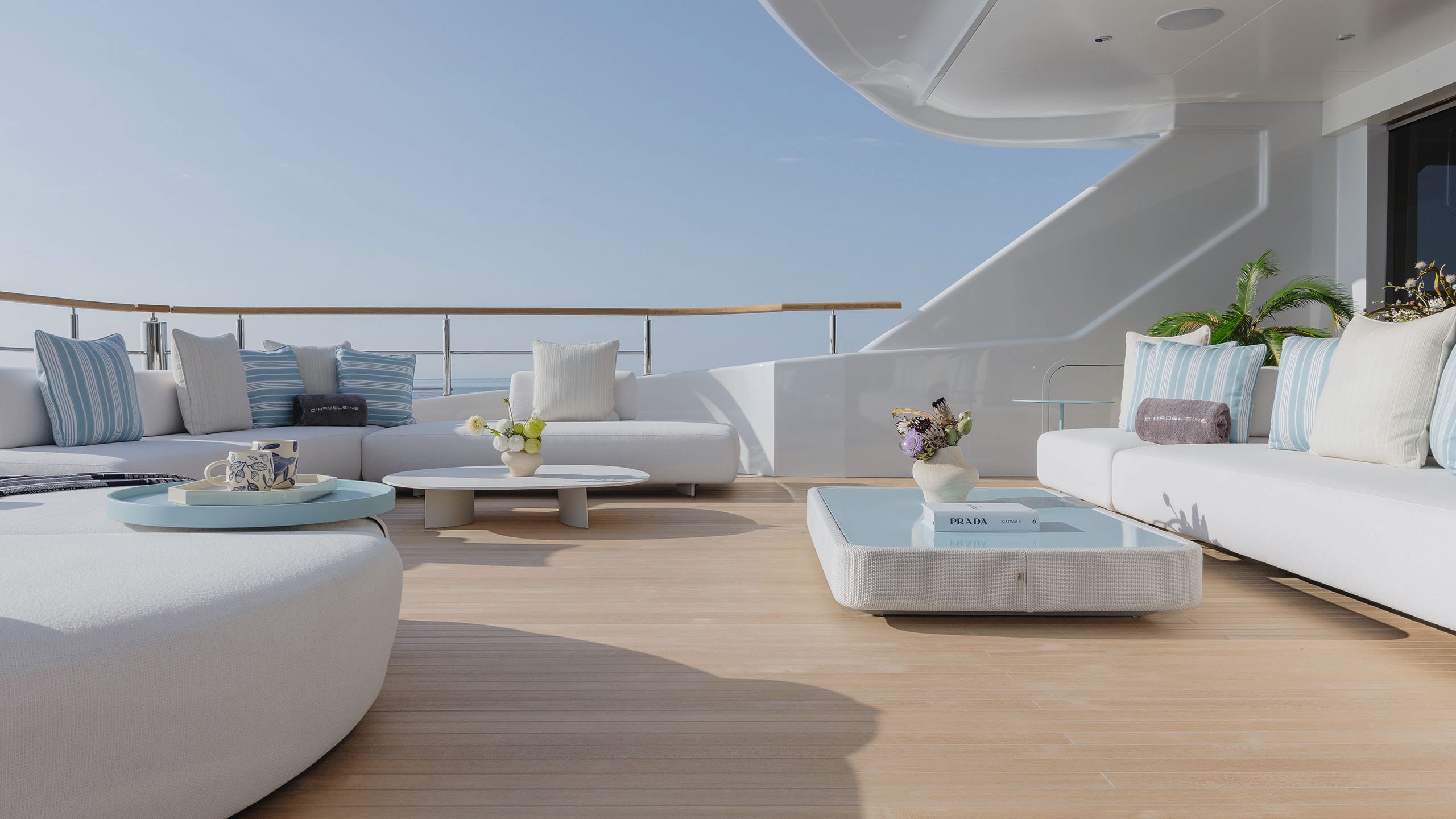 Side view of outdoor deck area with curved white sofas and low tables