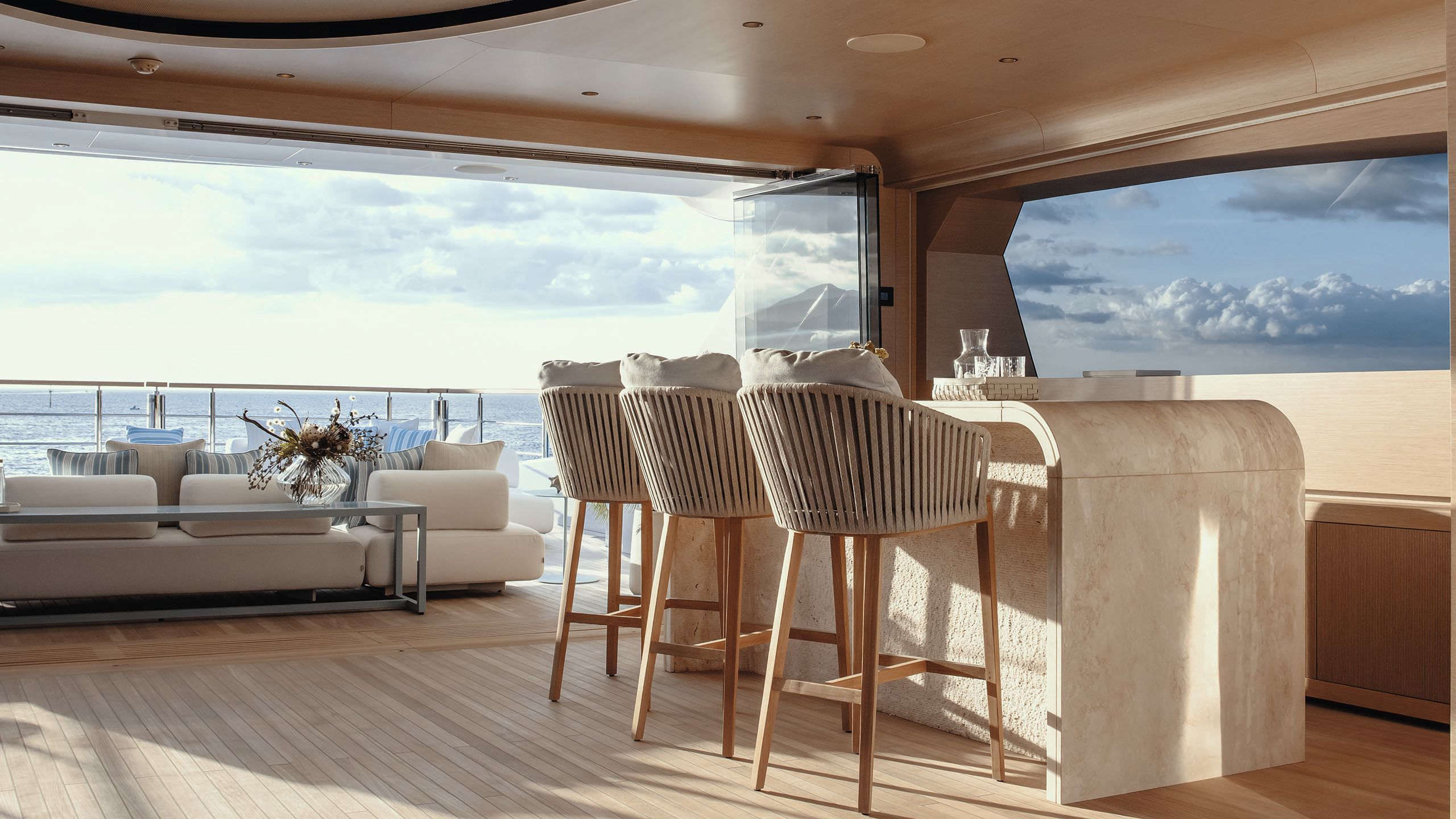 Side view of indoor-outdoor deck with curved bar top and three rattan high stools