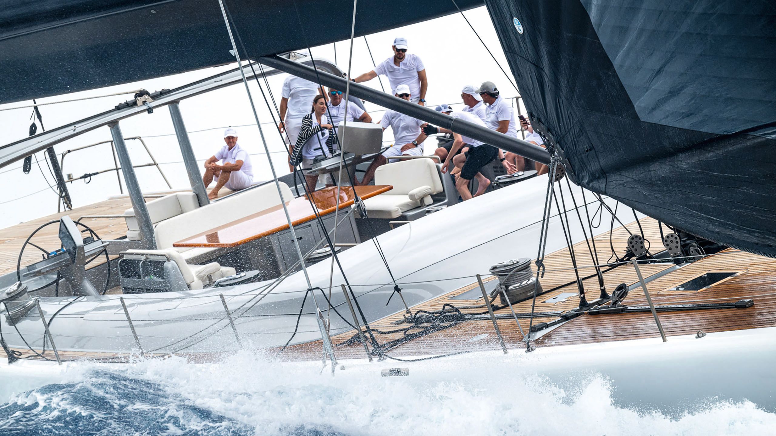 A close-up of Wally B on the water. The waves are choppy and the boat is tilted. There are several people in white polo shirts and shorts sitting on the deck