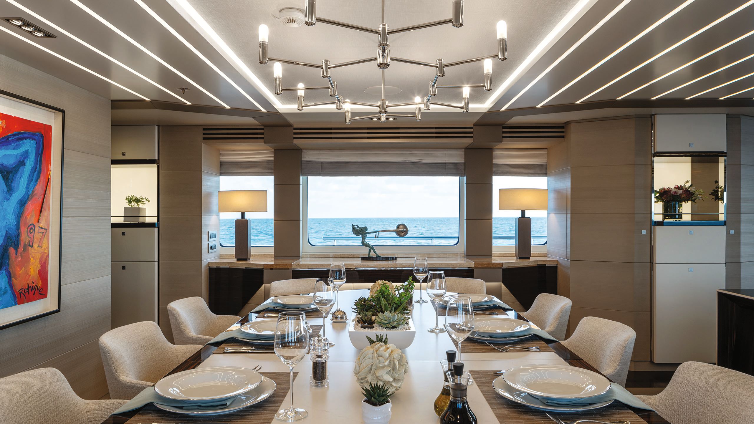 Wide shot looking down the dining table with the statue artwork in the centre of the window at the end