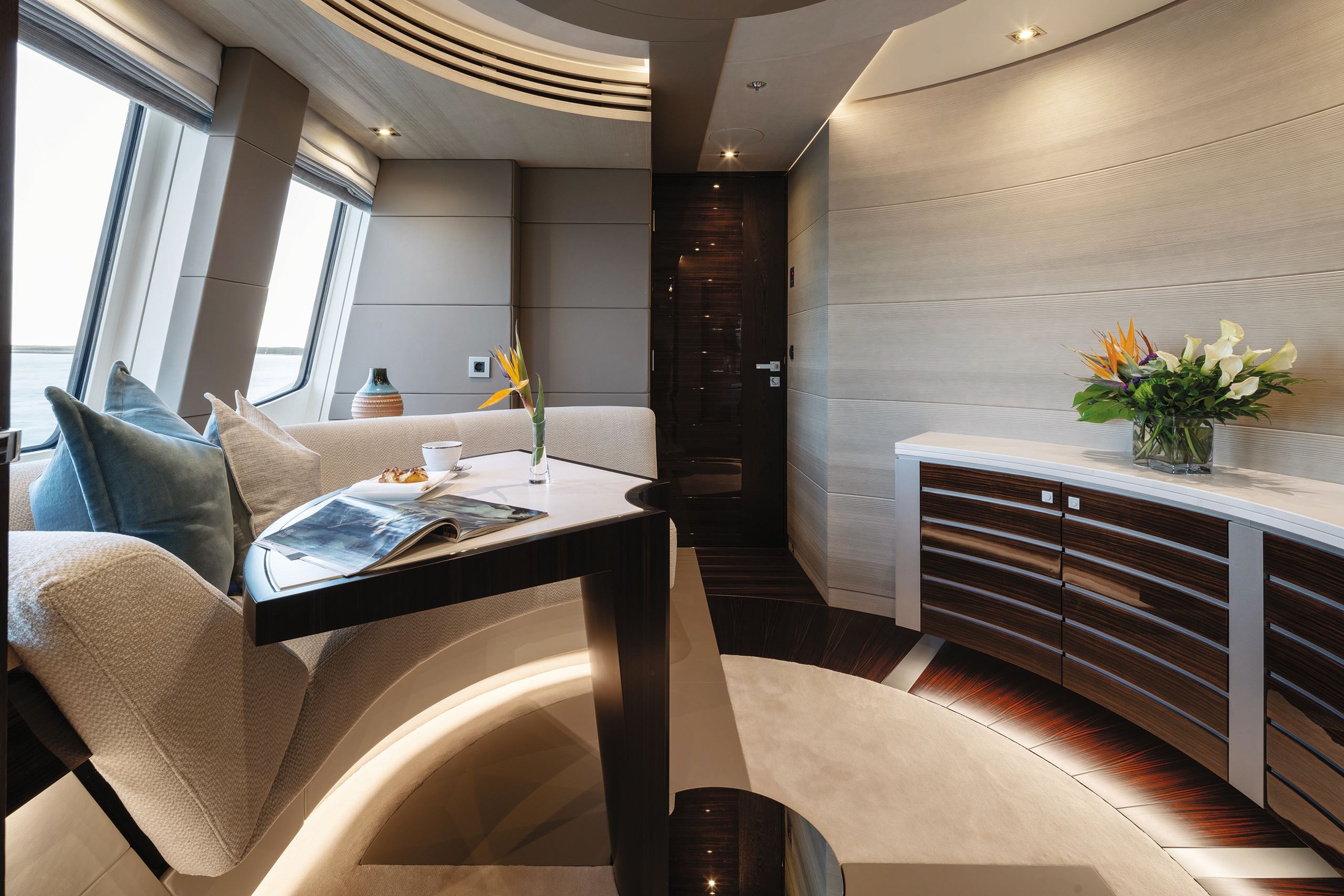 A small table in front of a curved, neutral soft chair