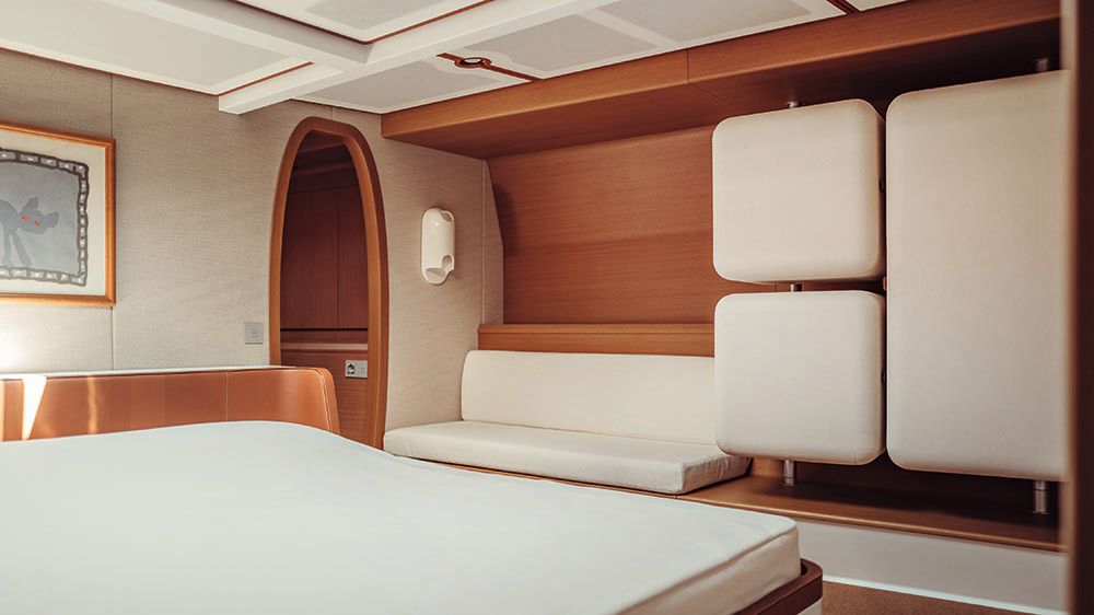 Wide shot of a bedroom with cream furnishings finished with teak wood and tan leather