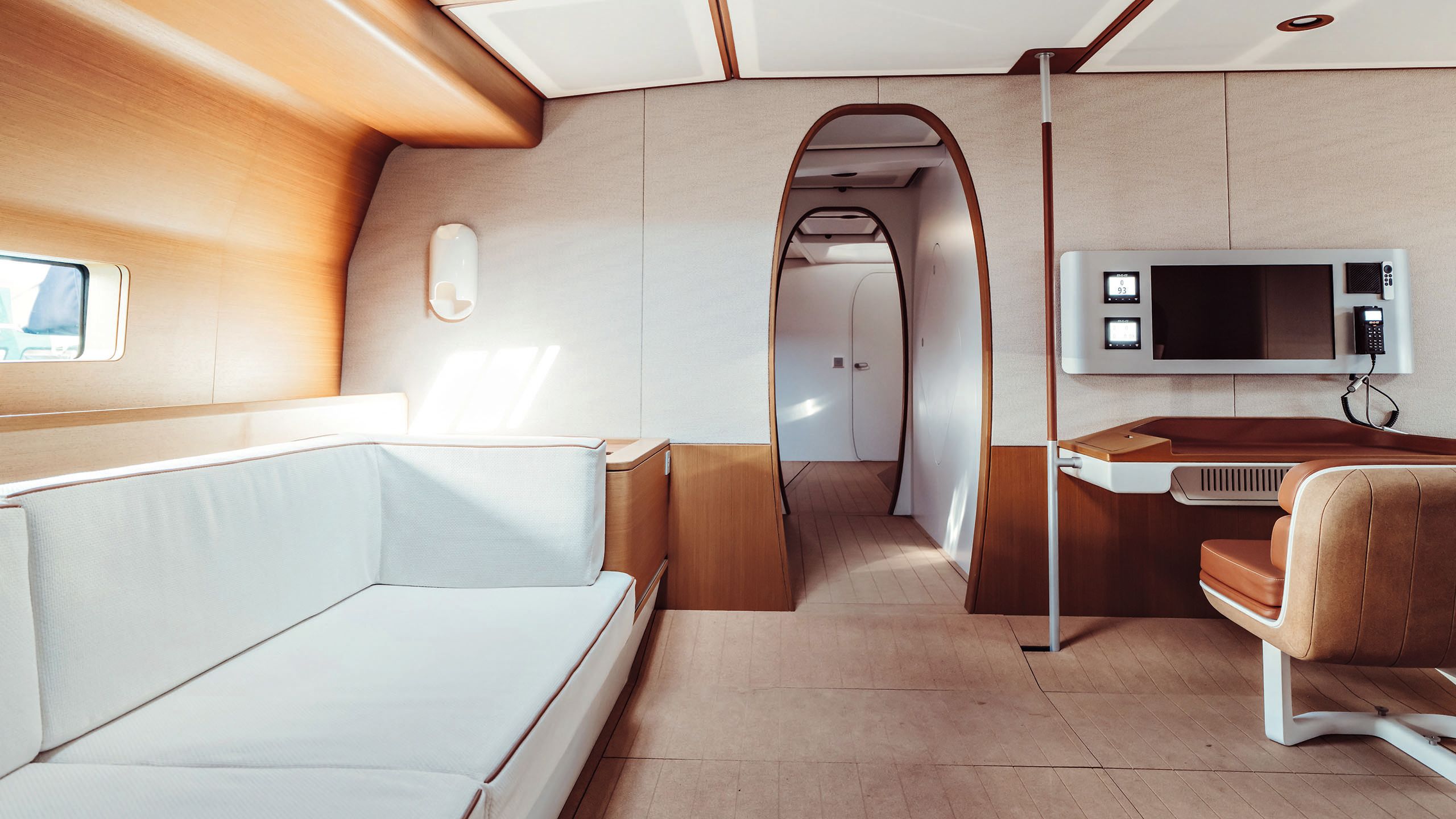 Alternative view of the room with a chair and control panel, with oval doorways in the background and a cream banquette seat on the left
