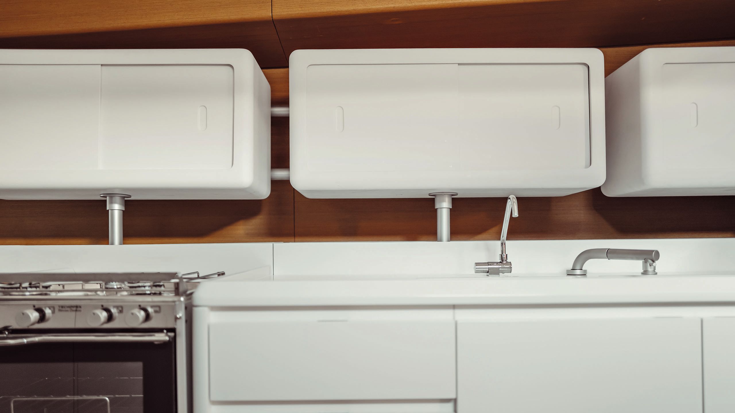 Looking face-on at a white kitchen counter with cupboards above and chrome oven to the left