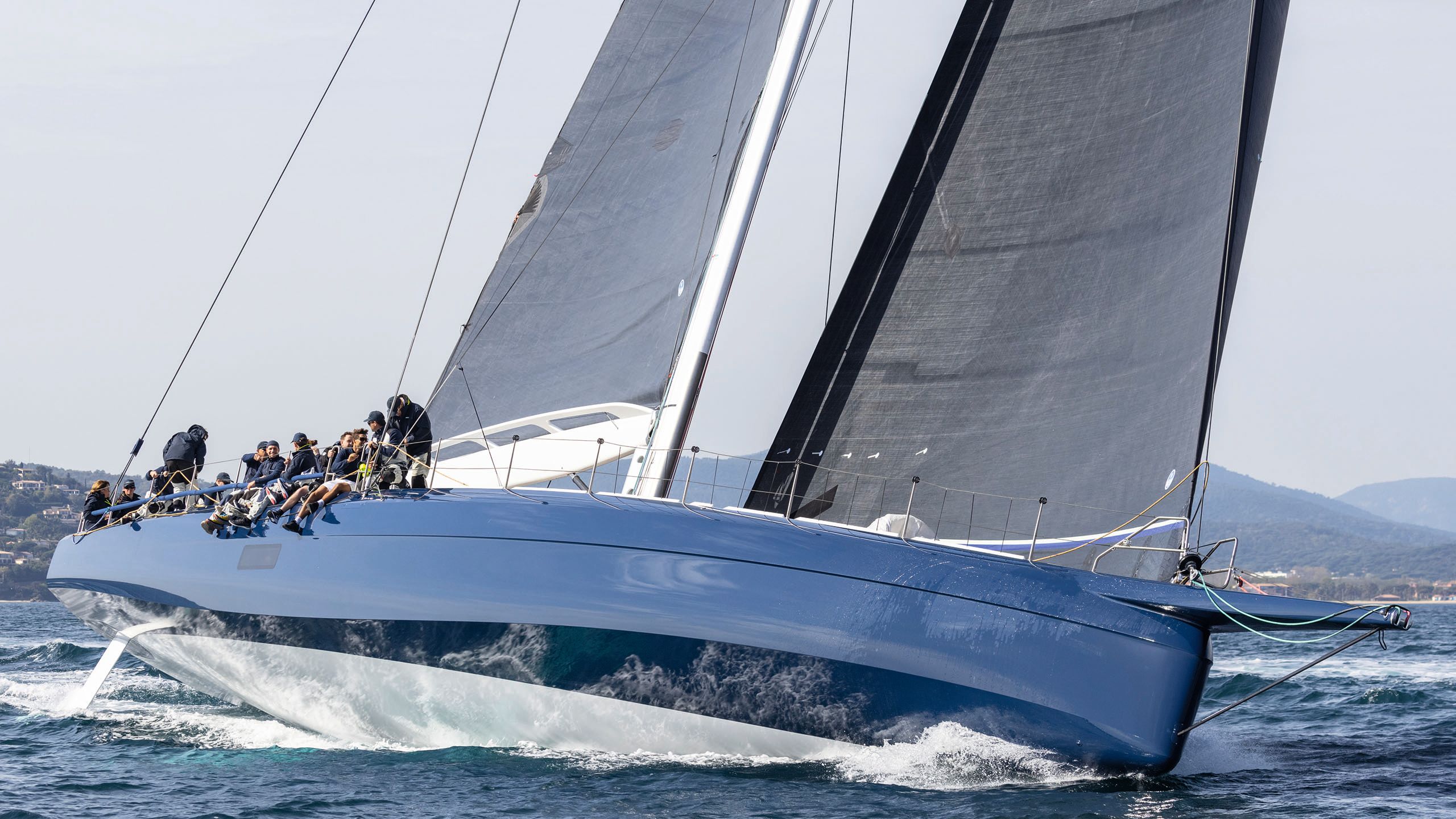 Side view of Magic Carpet E on the water with two dark sails up