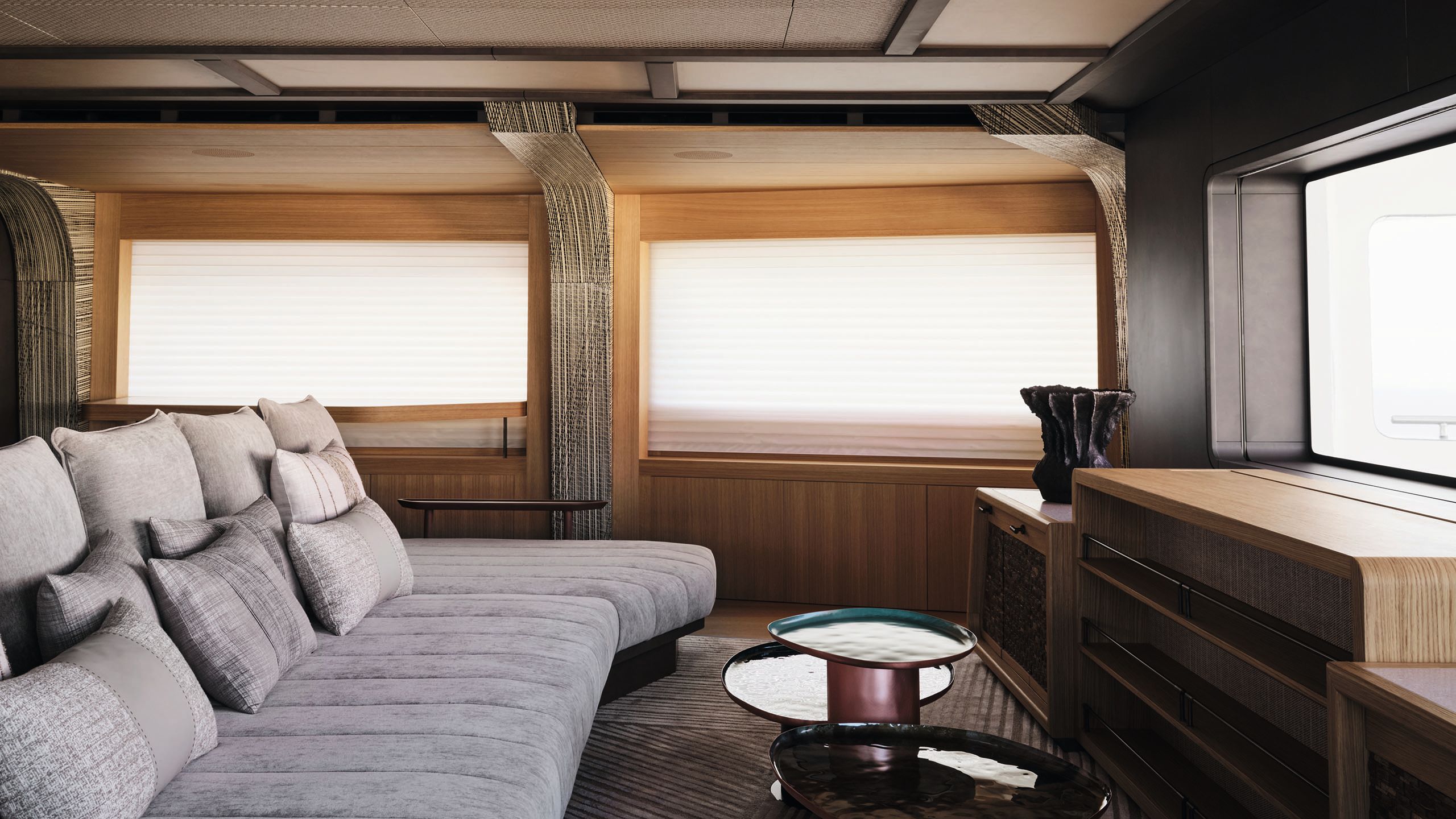 A large grey sofa opposite big, open windows