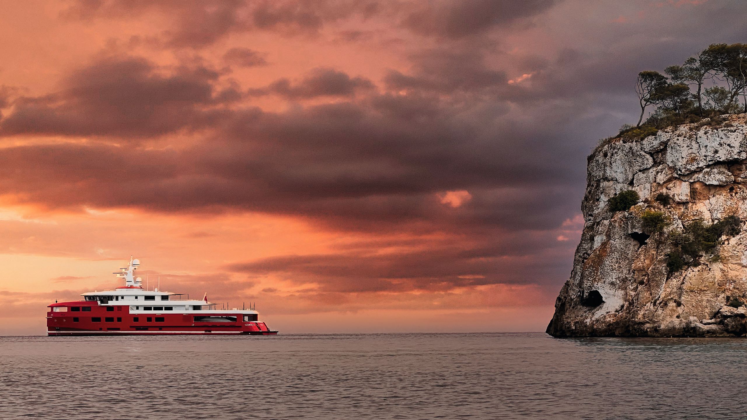 Wide shot of Akula on the water. The sky is red and orange