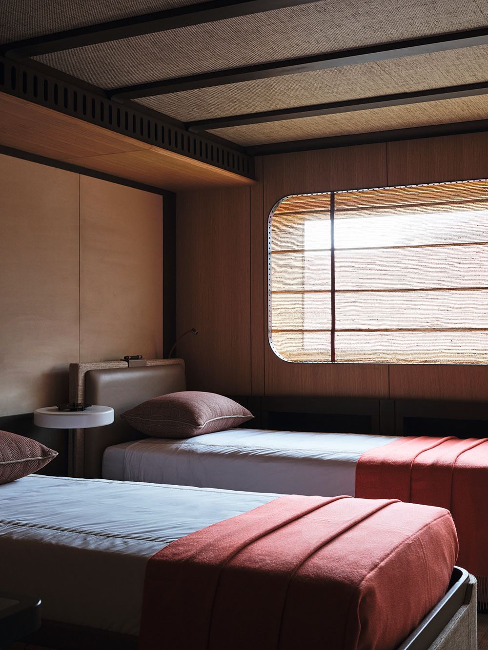 Twin beds made up with white and red linens and brown pillows
