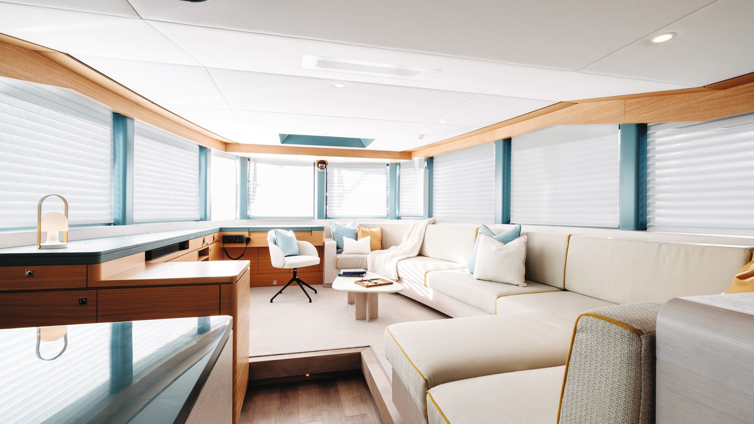 Large corner sofa in cream, blue and white cushions, and a teak desk that wraps around the room