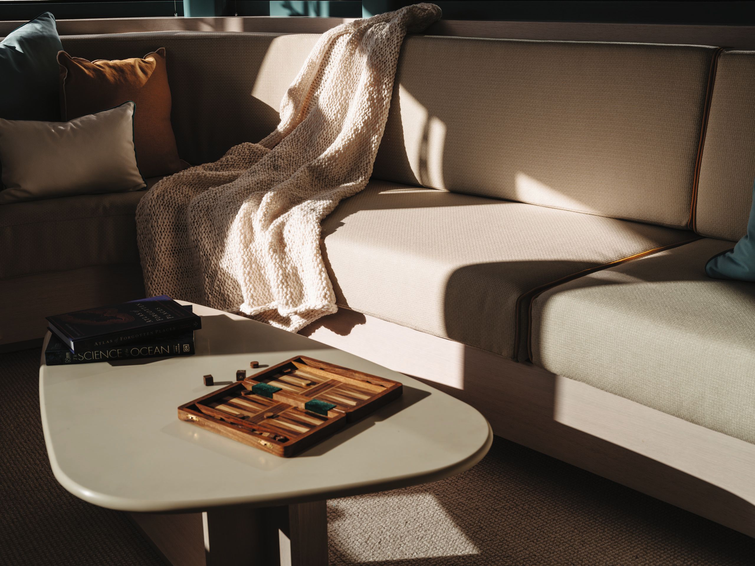 Close-up of the saloon's cream leaf-shaped coffee table. It is in front of the cream sofa which has a cream throw on it