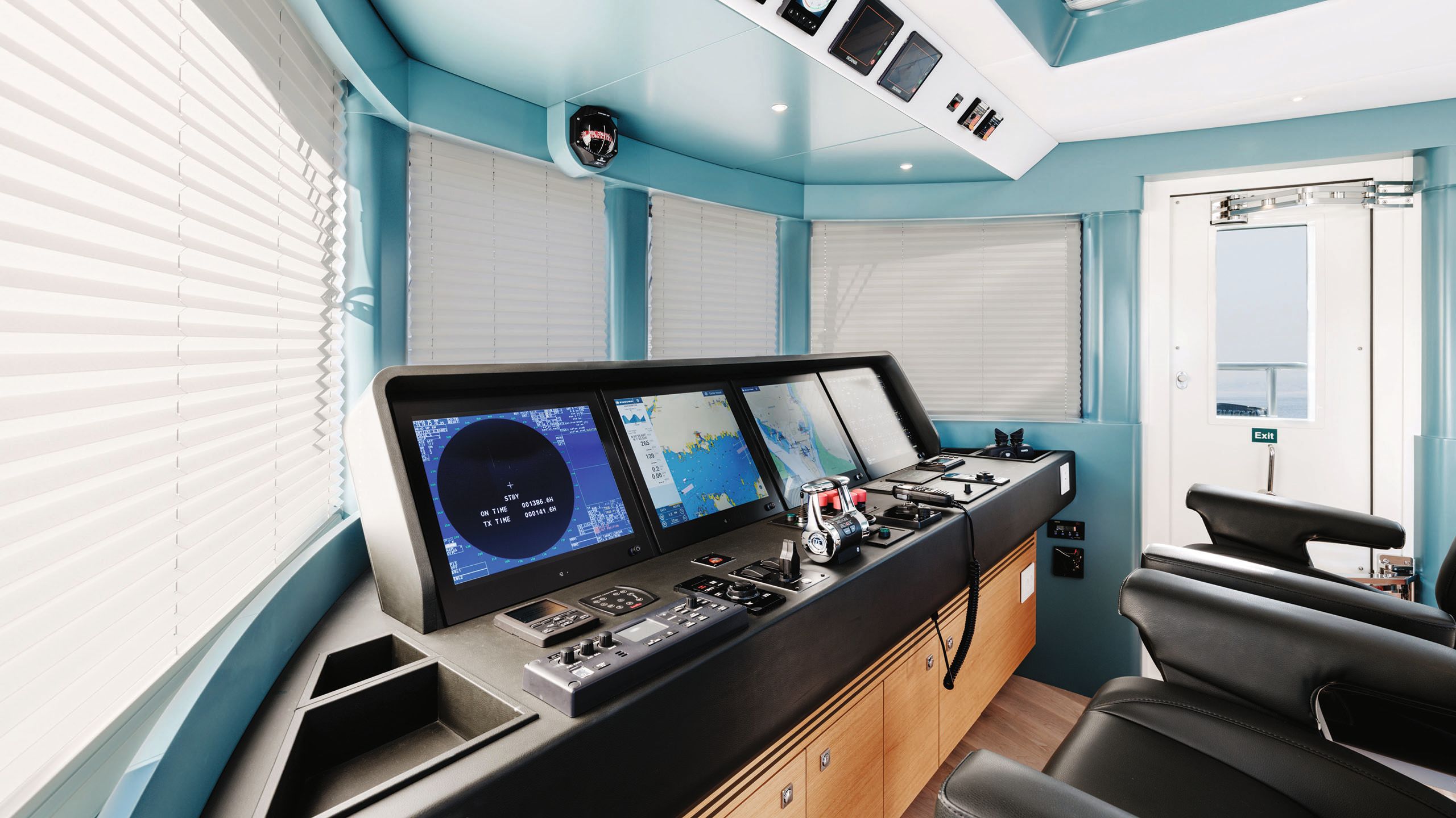 Teal walls surround three screens and controls