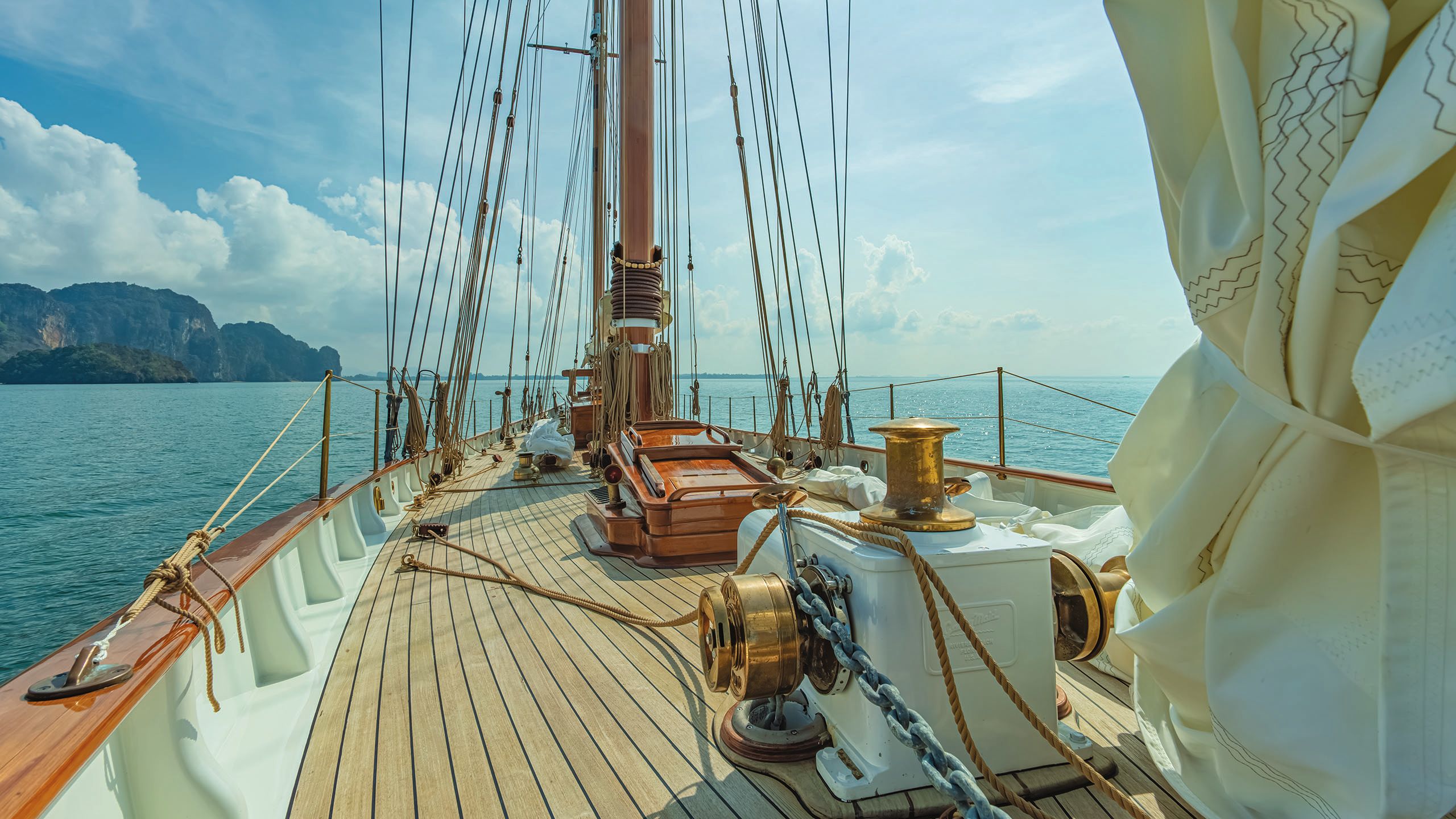 Bronze winches at the forefront of the picture which also shows ropes and the sail tied up