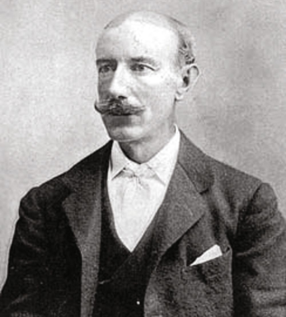 Black and white portrait of Lord Dunraven.  He has a moustache, thinning hair and is wearing a dark suit and white shirt.