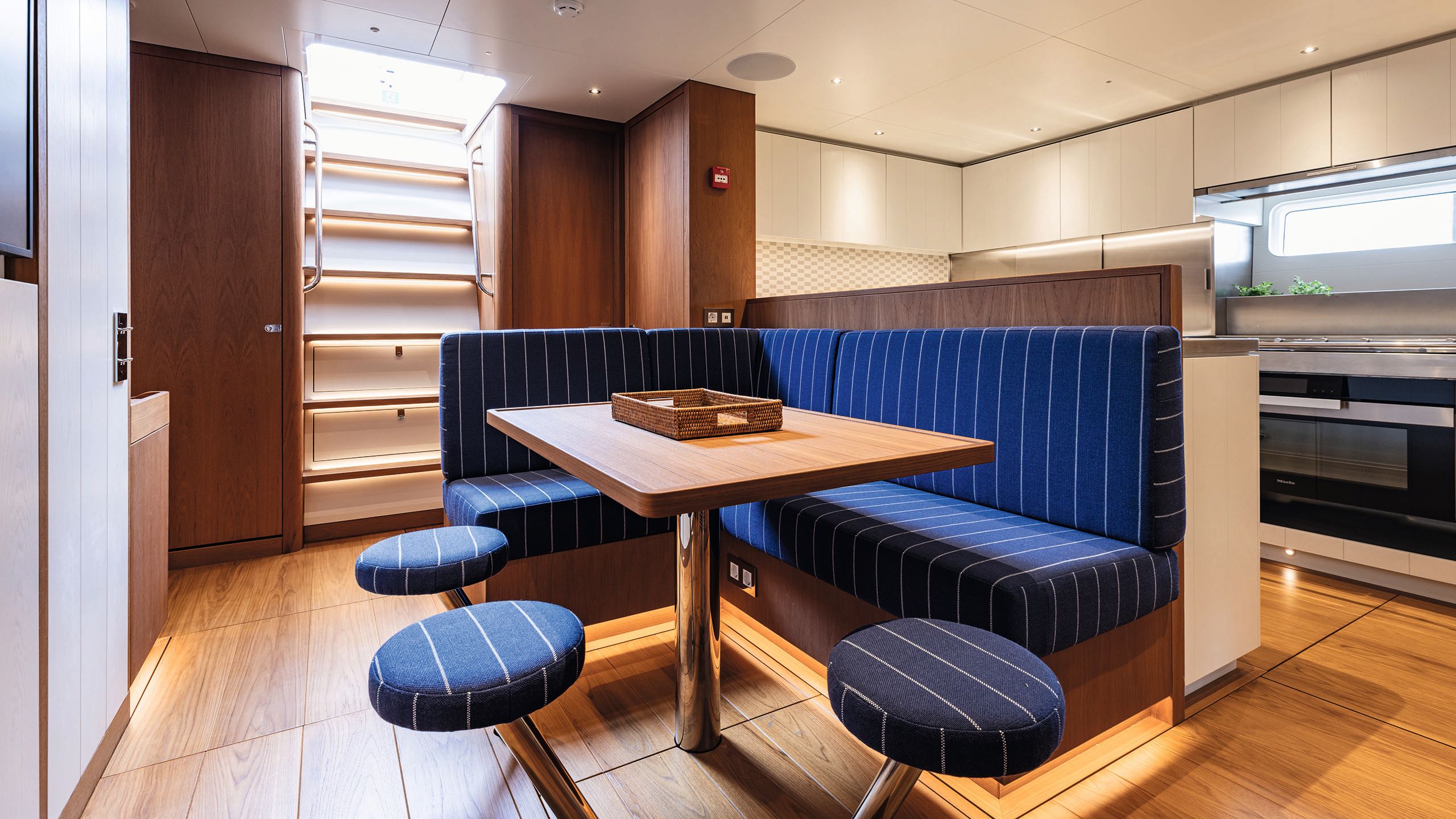 Downstairs interior of BeCool showing an L-shaped banquette with table and stools. The fabric is blue with very thin white stripes