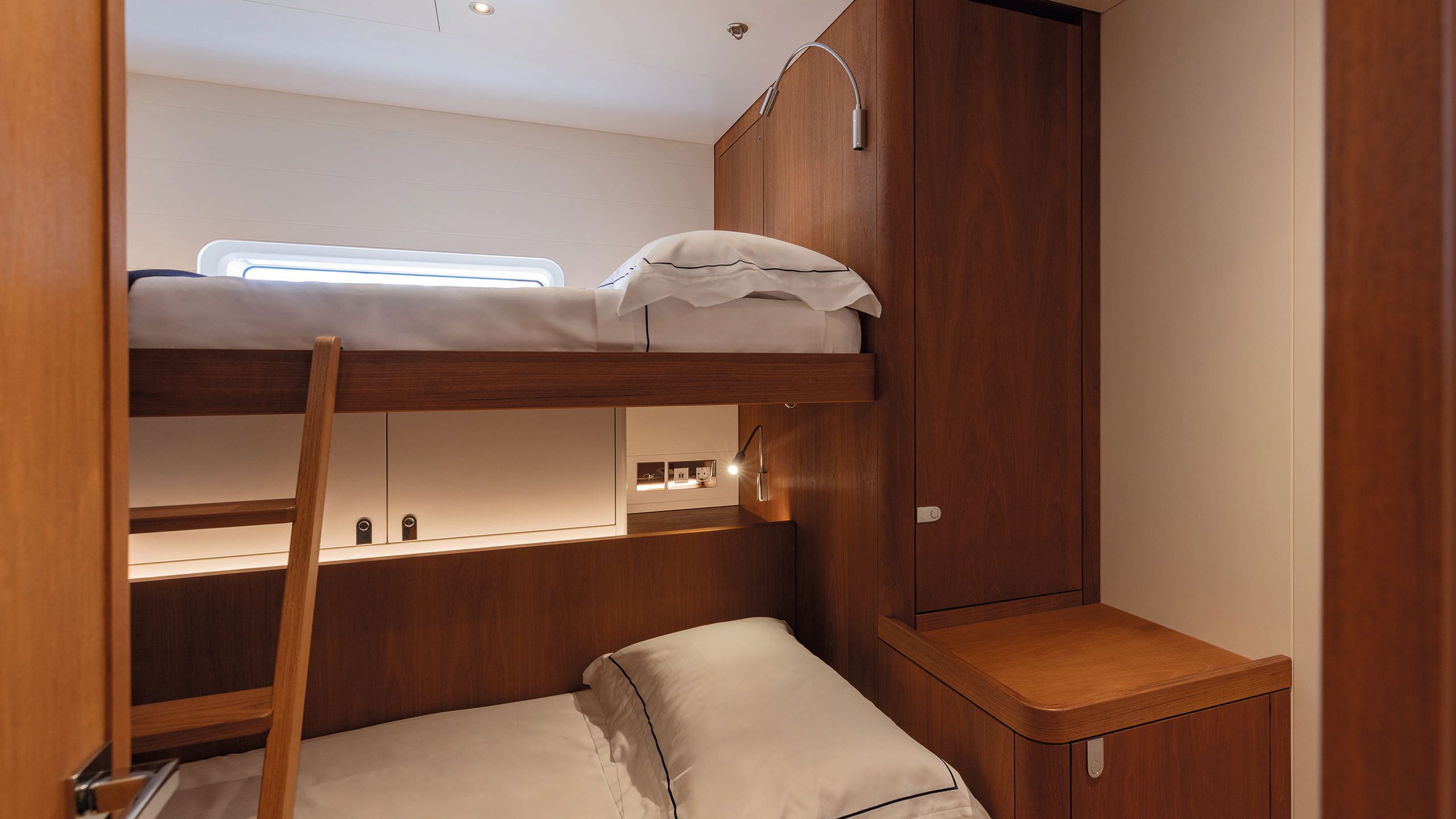 Twin bunk beeds with white sheets and wooden ladder up to the top bunk