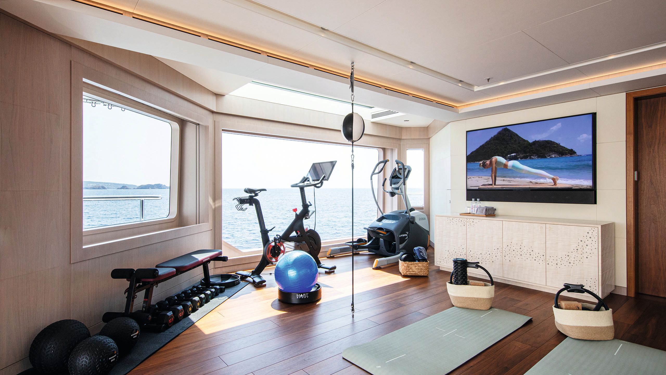 Gym room with exercise bike, cross-trainer, bench with dumbells, exercise mats and various small pieces of equipment