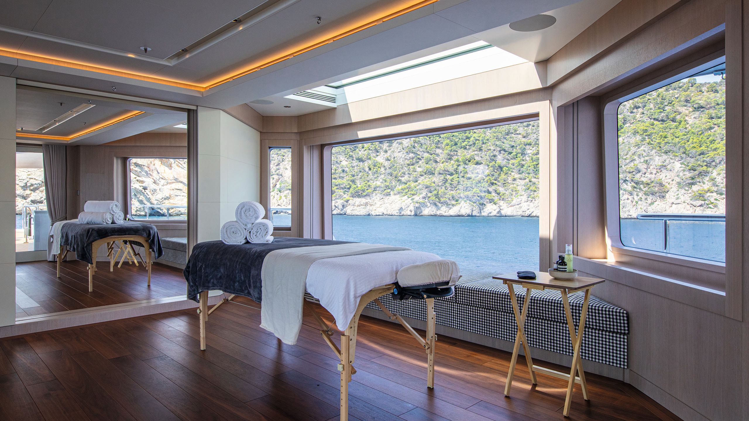 A massage table set up in the middle of a room with towels rolled on top