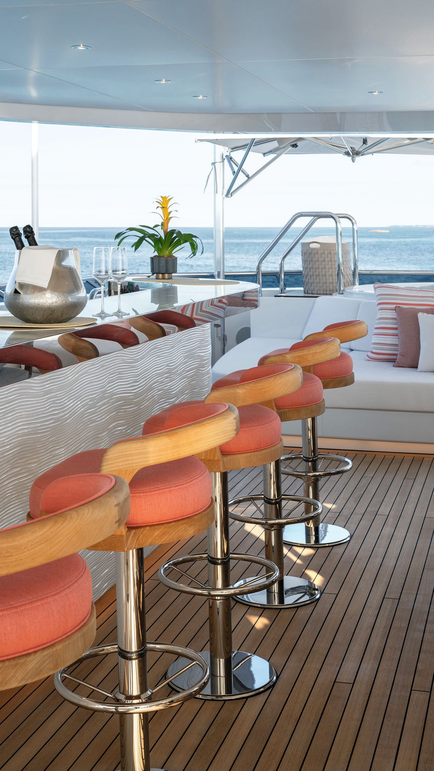 Looking down the side of the bar. There are four high stools upholstered in orange