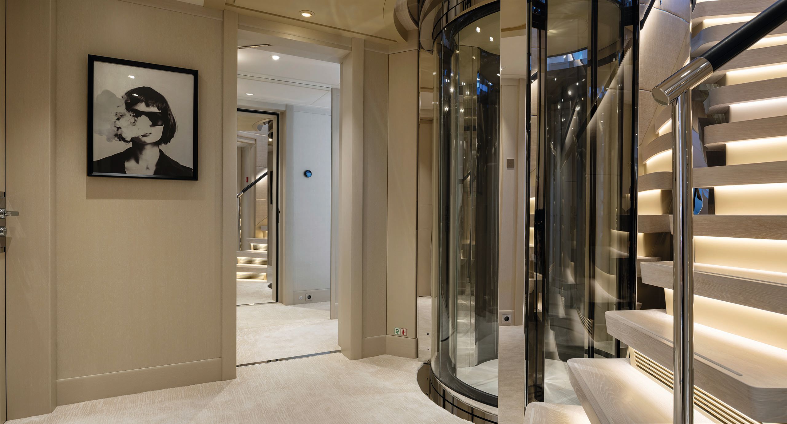 Side view of the glass-sided lift with a staircase running next to it