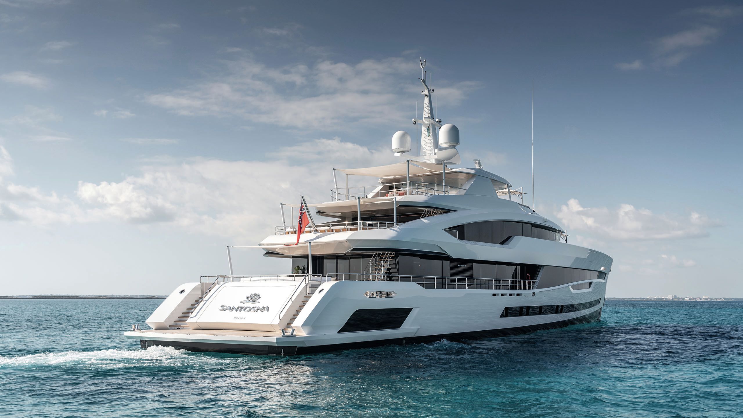 Partial side view of Santosha. A helicopter is flying right above it