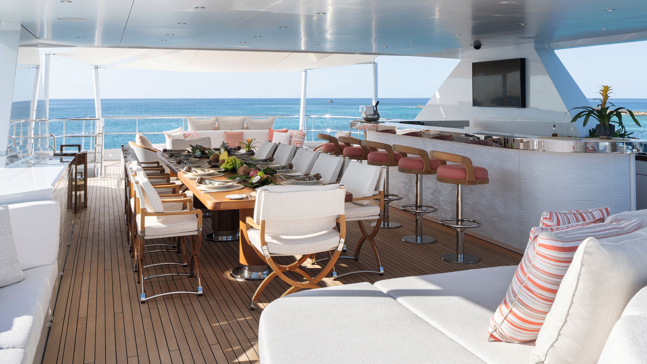 Long table on the deck with upholstered chairs around it. The table is set for 12