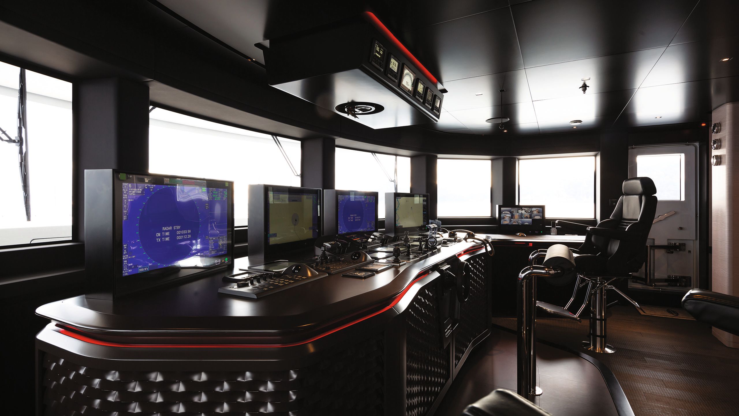 Several black screens and navigational tools in front of a large black leather chair