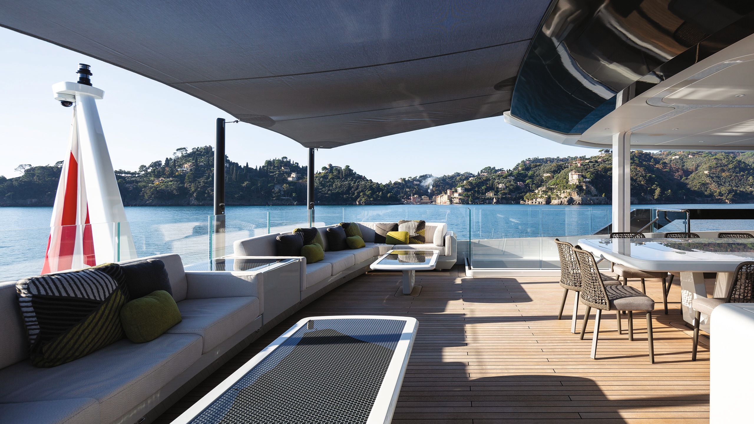 Grey sofas on a covered outdoor deck facing a dining table